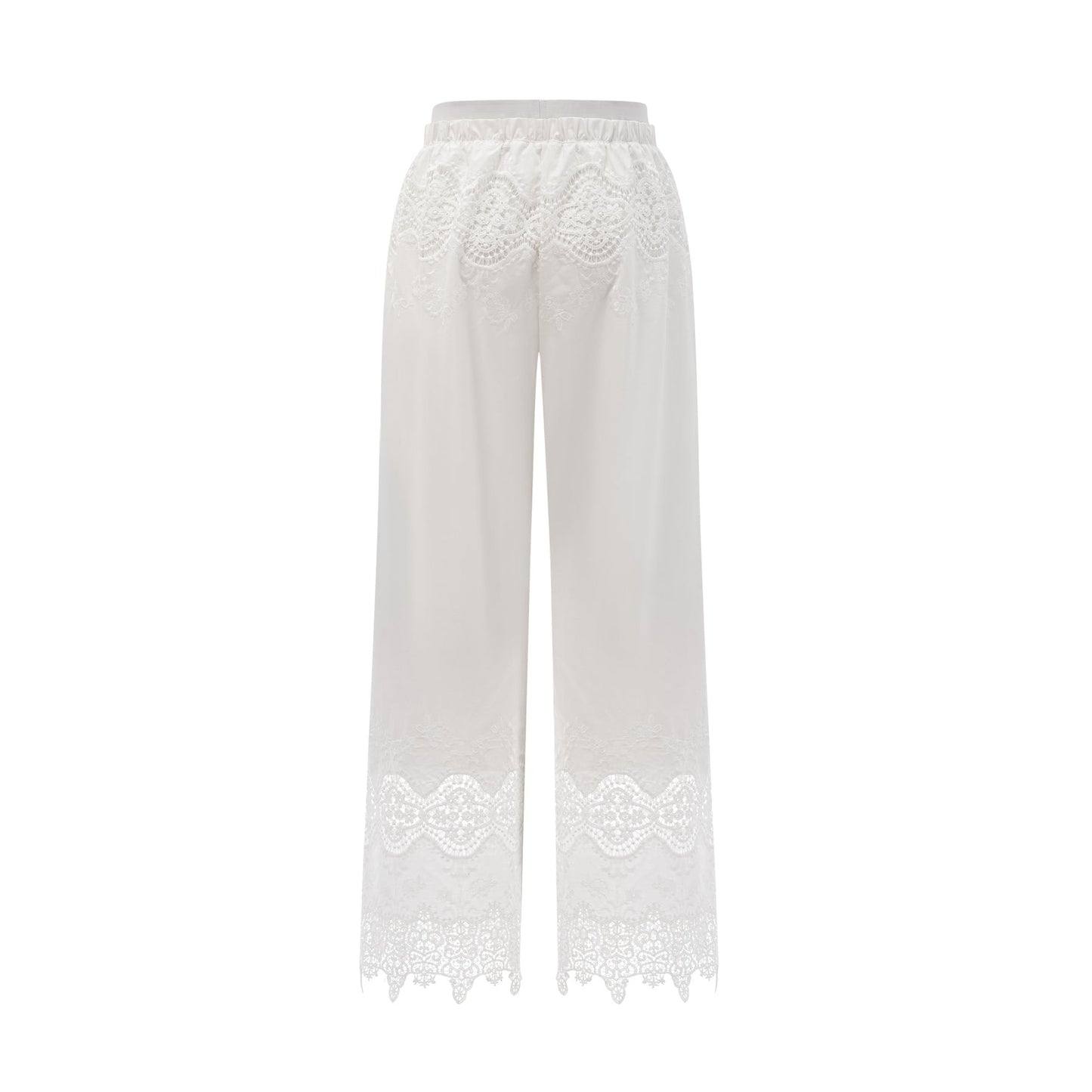 Woman wearing a white lace trimmed cropped top and matching trousers with cutout details