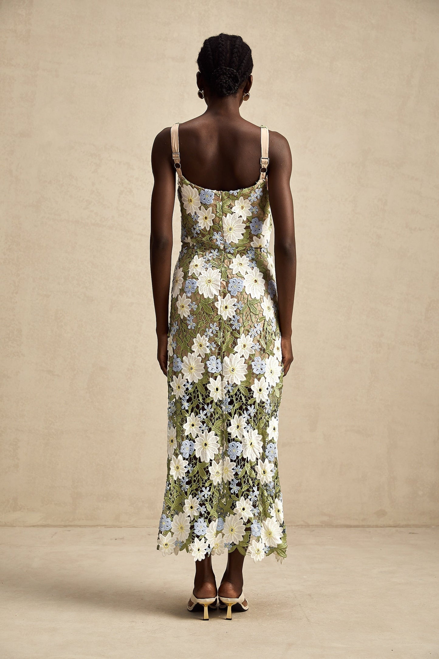 Woman wearing a white midi dress with floral embroidery and cutout details