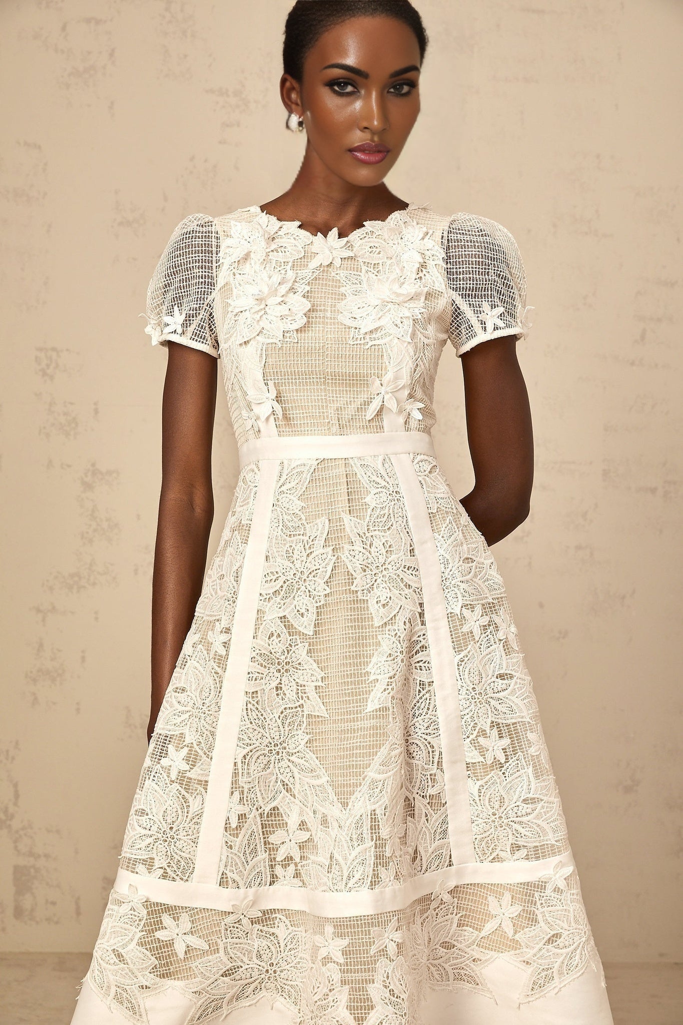 Woman wearing a white midi dress with floral embroidery details standing in a relaxed pose