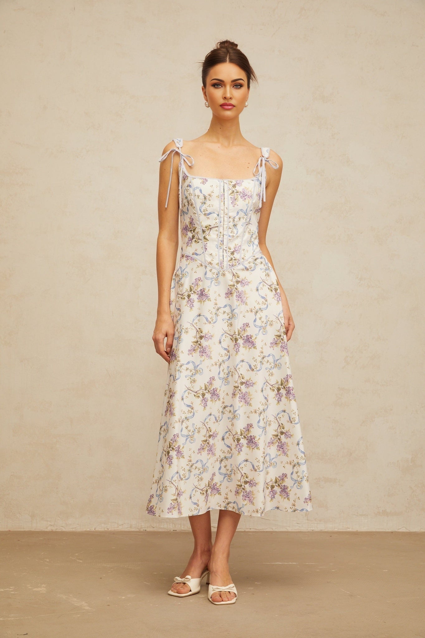 Woman wearing a white midi dress with floral print and flared skirt design by Bruyere