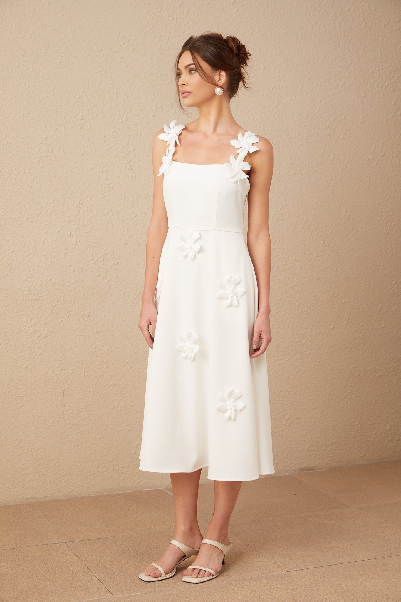 Woman wearing a white midi dress with square neckline and faux flower embellishments