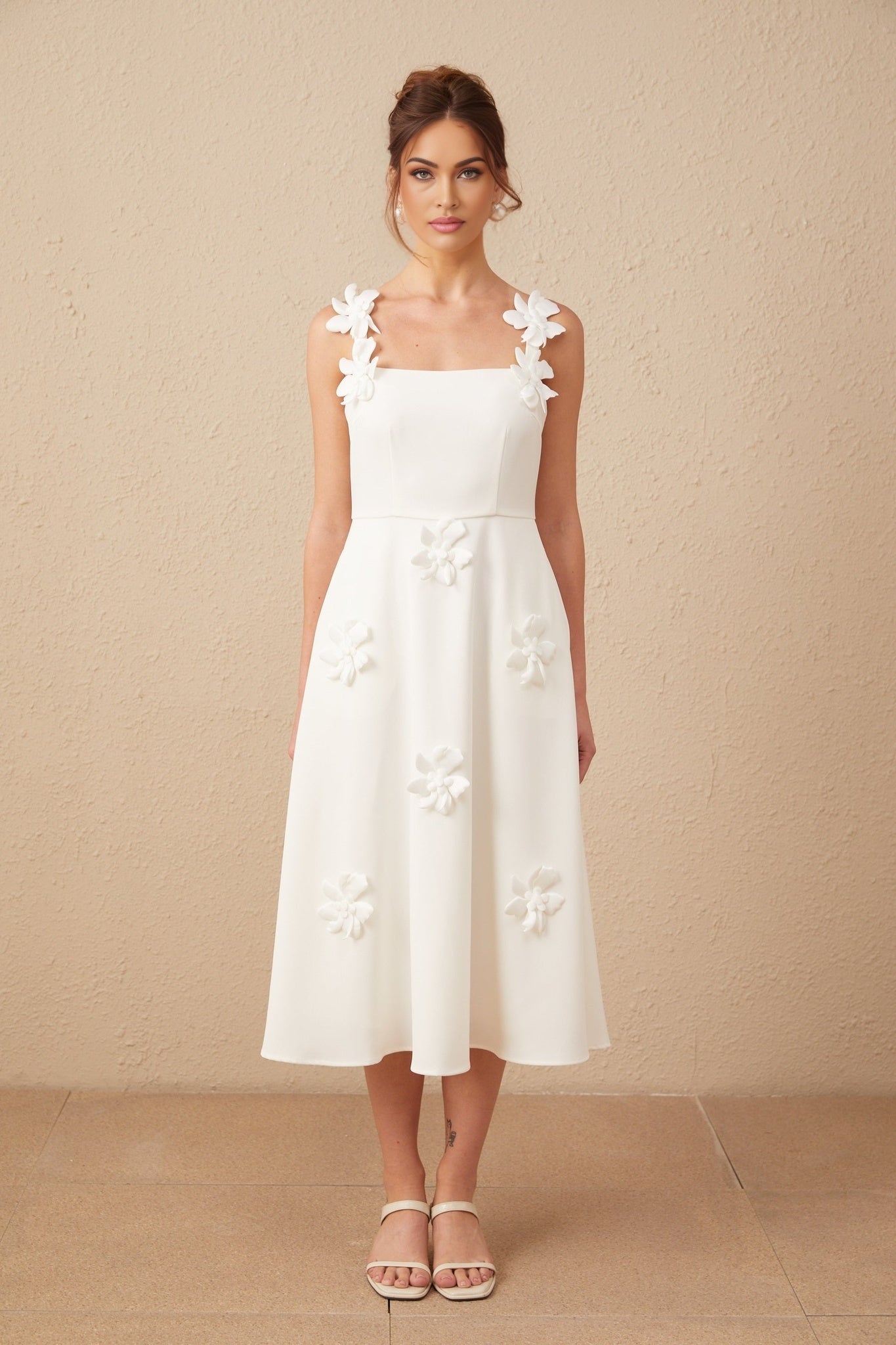 Woman wearing a white midi length dress with square neckline and floral design featuring faux flowers