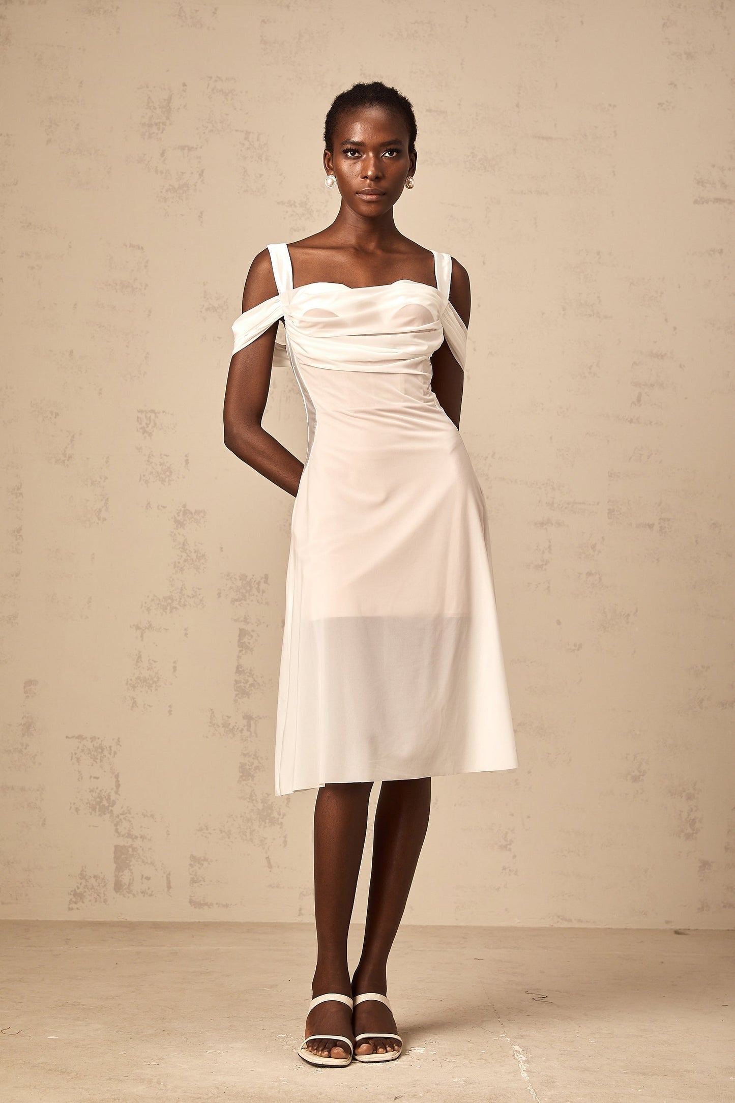 Woman wearing a white semi sheer ruched midi dress with gathered details standing in a neutral pose