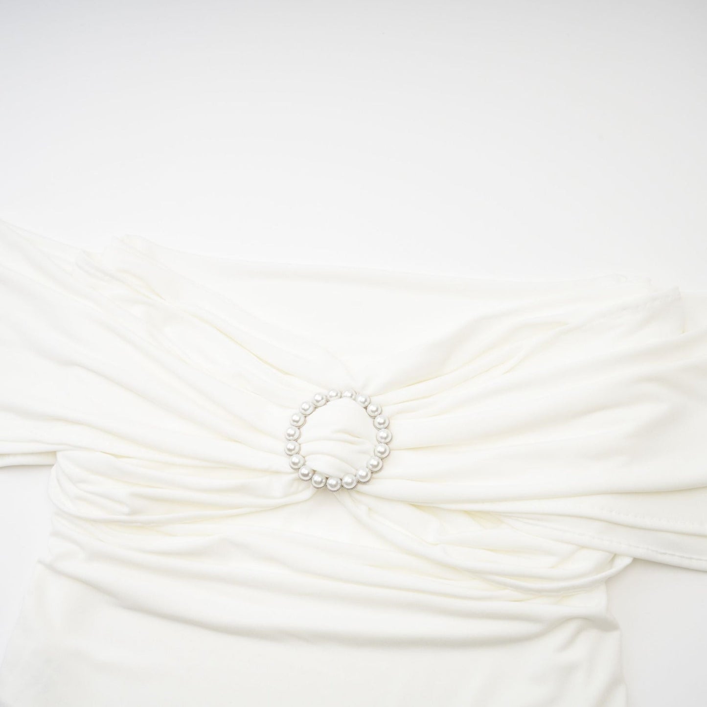 Woman wearing a white sleeveless top with gathered details on the neckline and shoulders