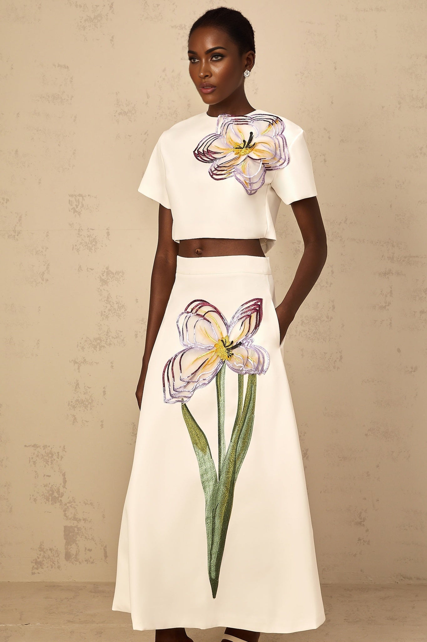 Woman wearing a white twopiece outfit with sequin floral embroidery details on both top and bottom matching set