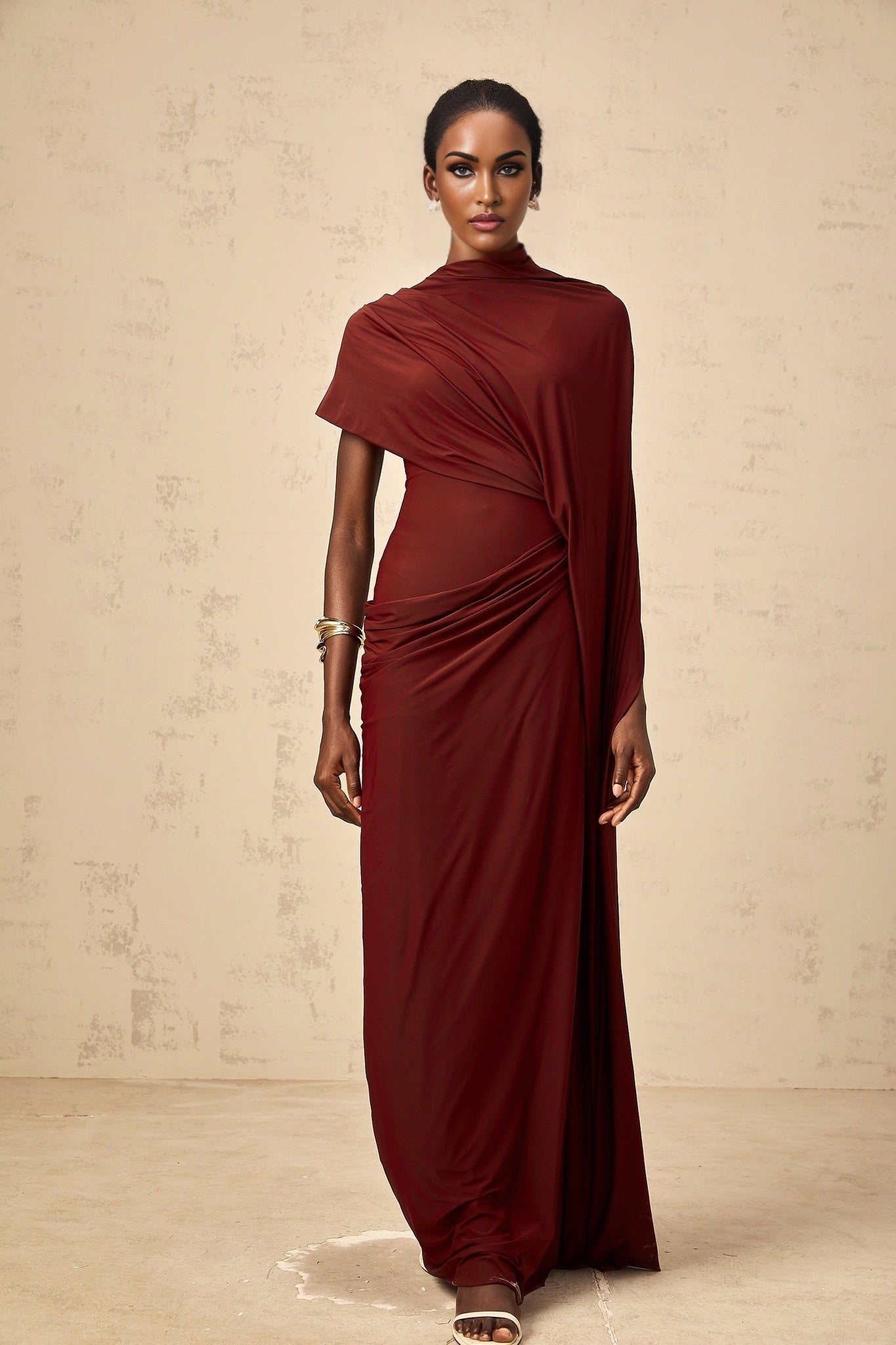 Woman wearing an asymmetrical black dress with attached draped cape forming a matching set
