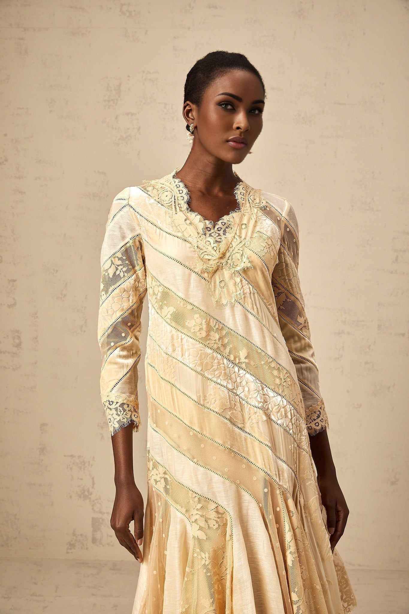 Woman wearing beige midi dress with diagonal stripes and panelled design