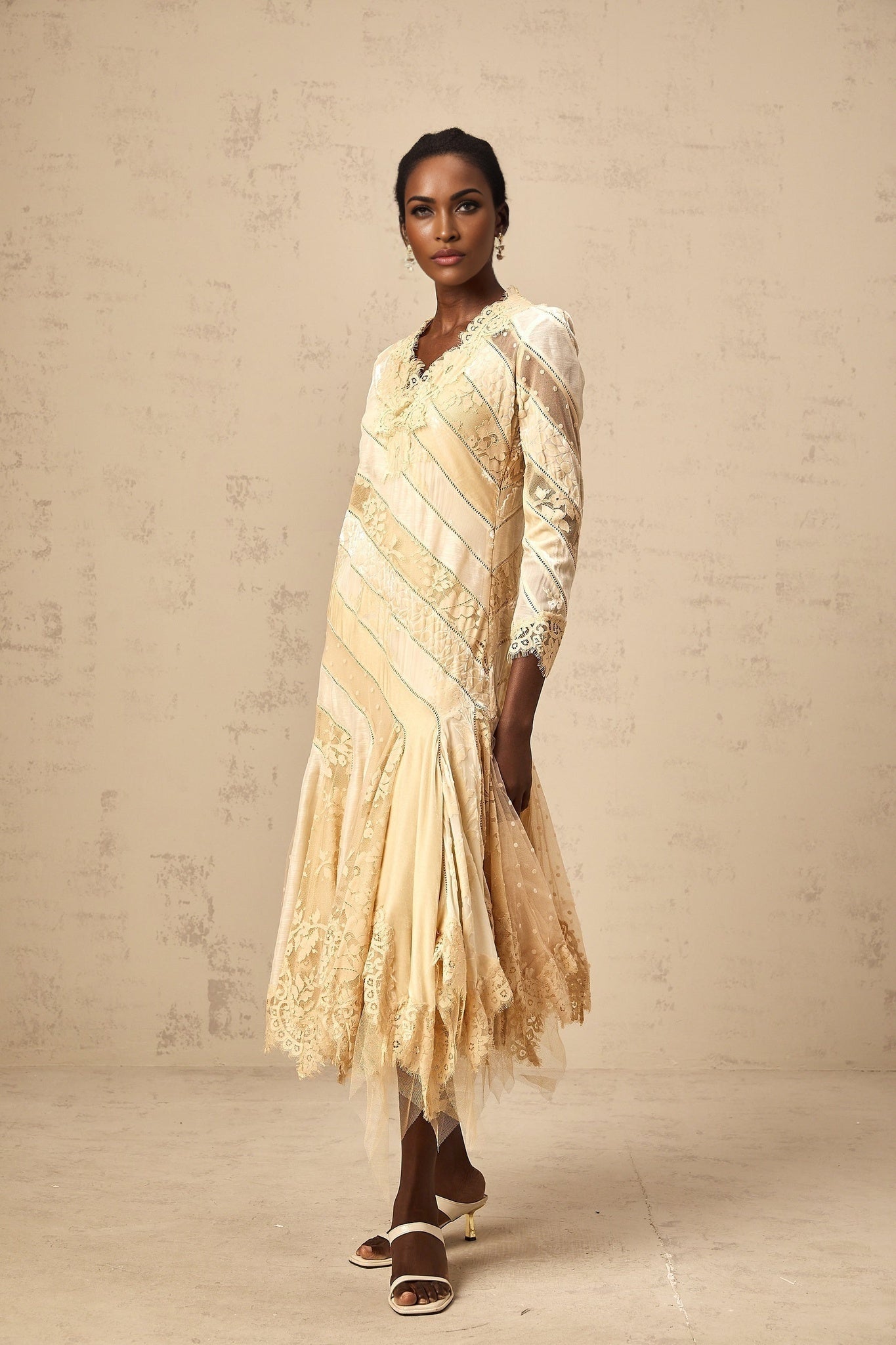 Woman wearing beige midi dress with diagonal stripes and panels