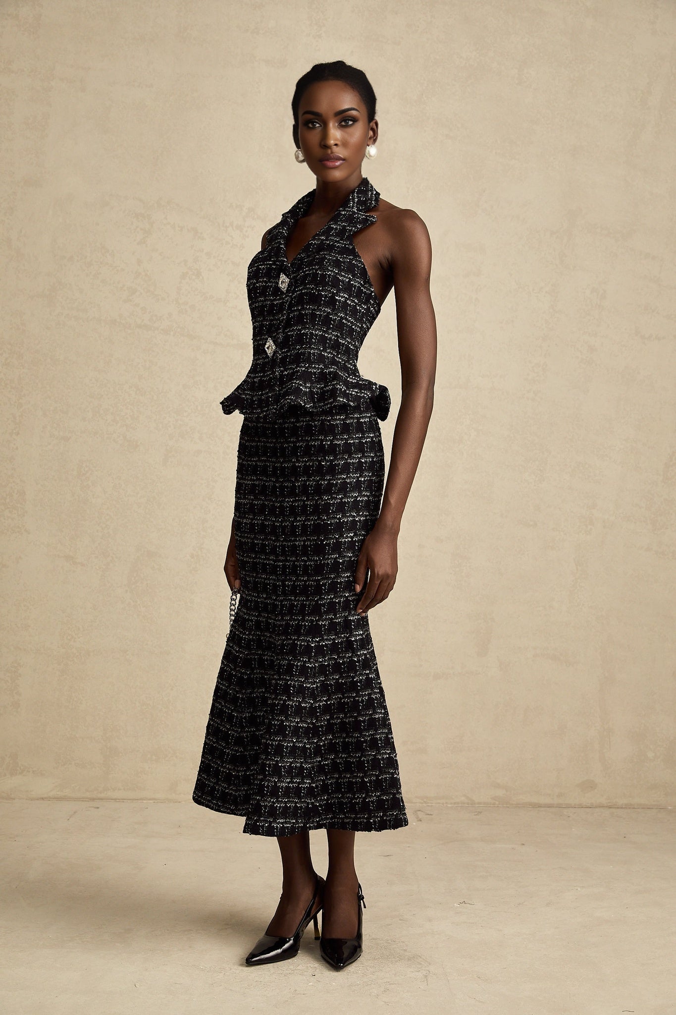 Woman wearing black and white checked tweed vest top paired with matching skirt set against plain background