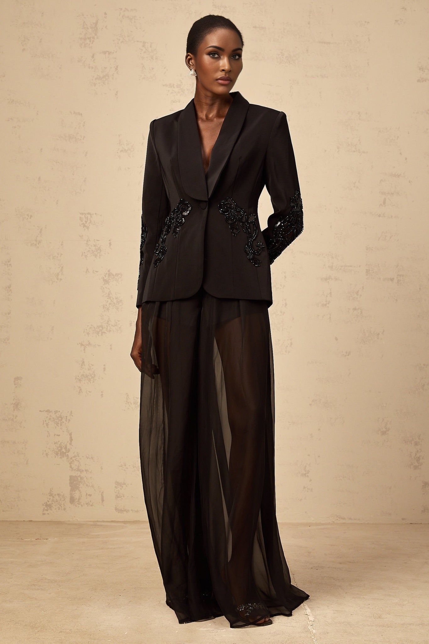 Woman wearing black blazer and trousers set with tulle panels and embellishments