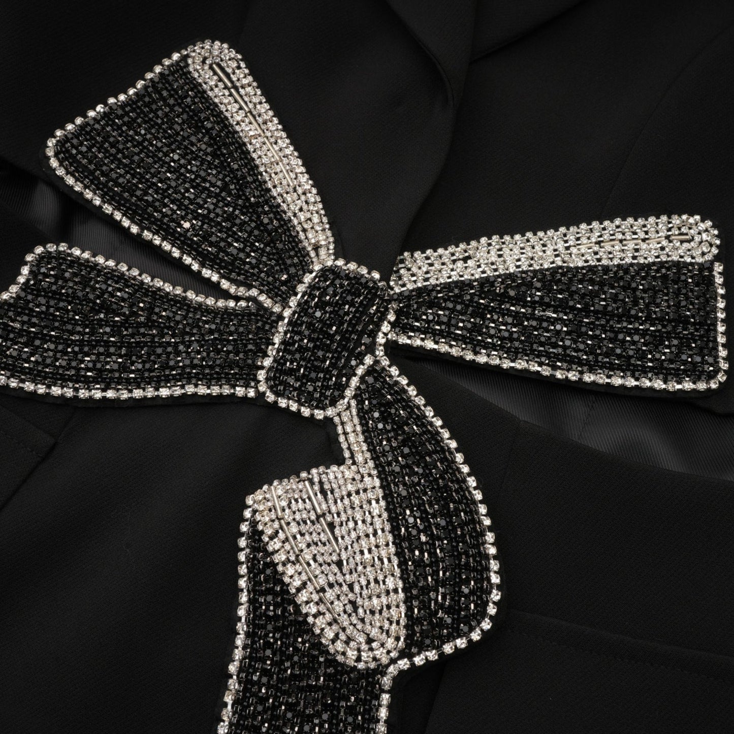Woman wearing black blazer with cutout details and decorative bow accent