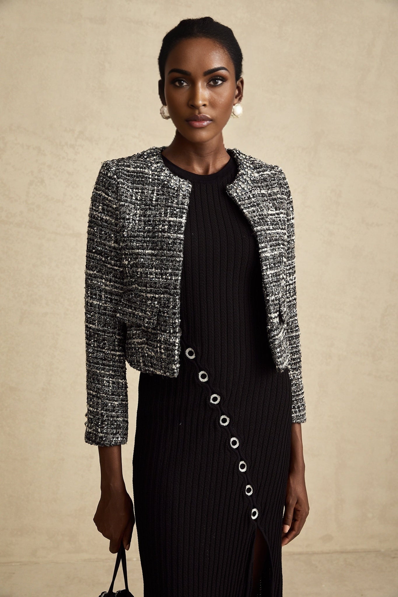 Woman wearing black bouclé tweed jacket with textured fabric and classic tailored design
