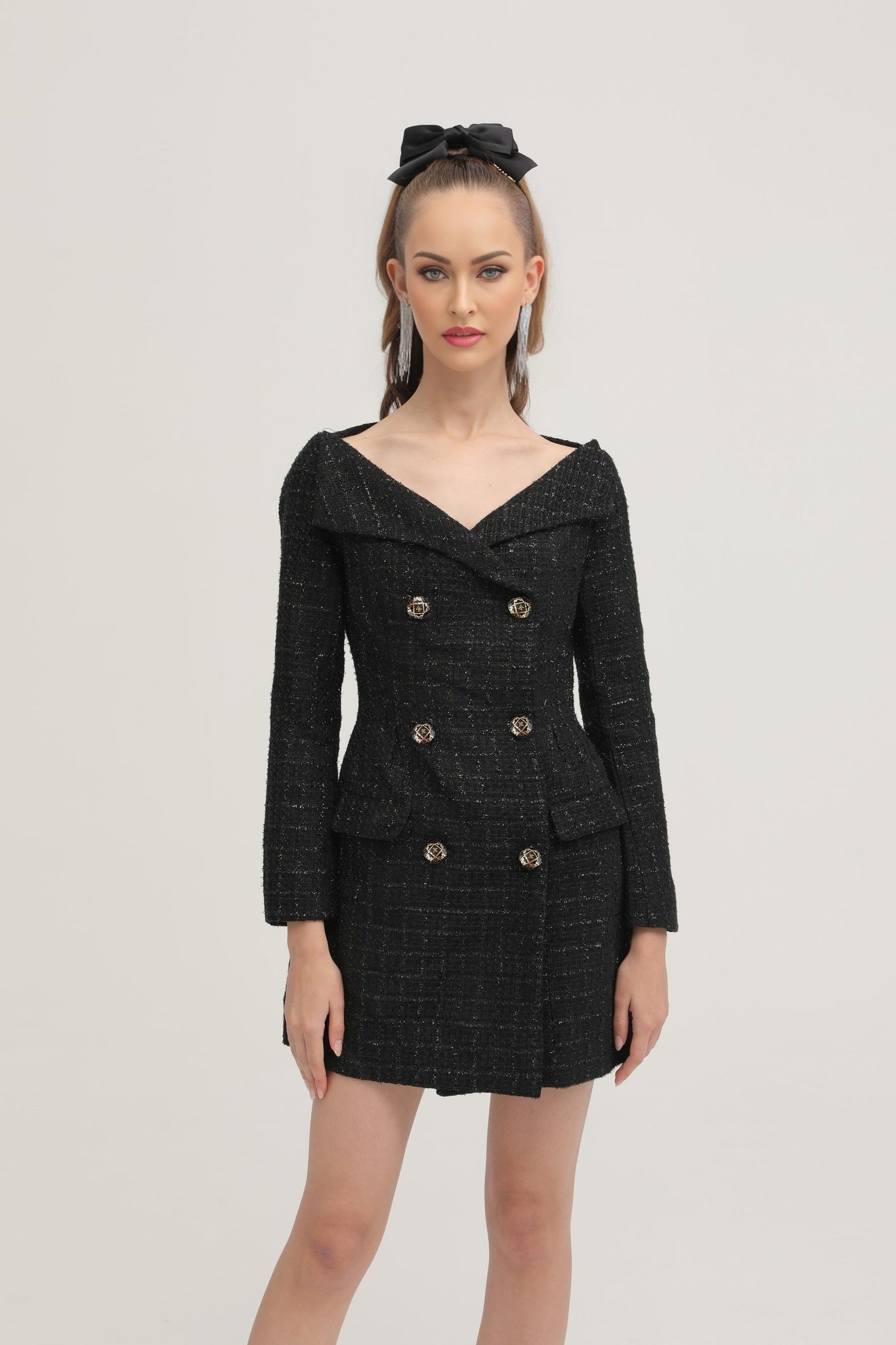 Woman wearing black double breasted coat dress with long sleeves and knee length skirt