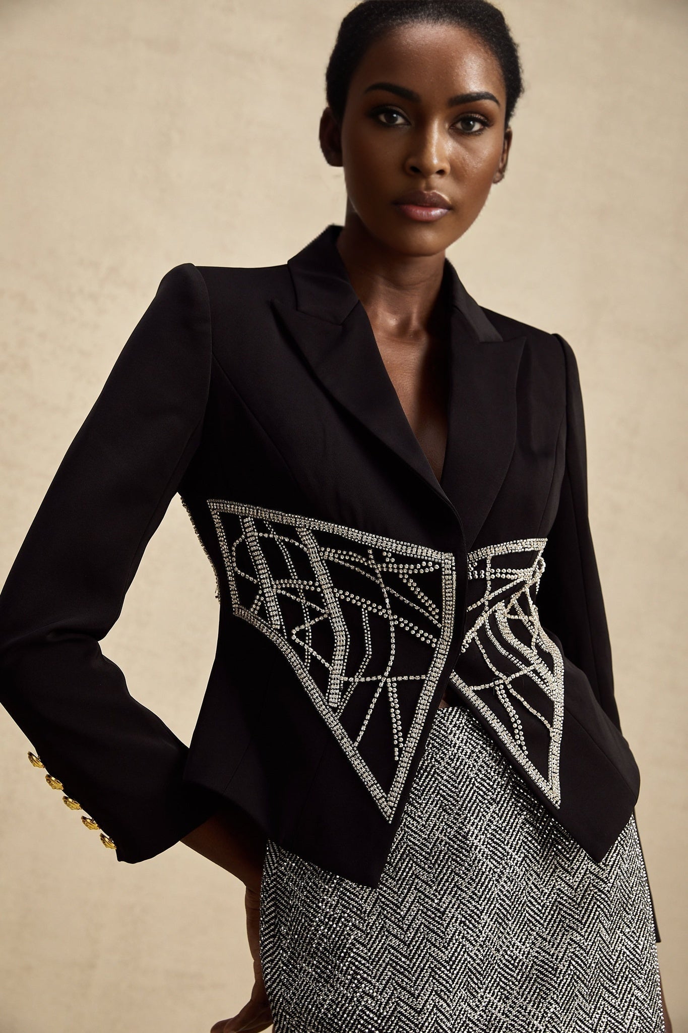 Woman wearing black embellished jacket with cinched waist and decorative details