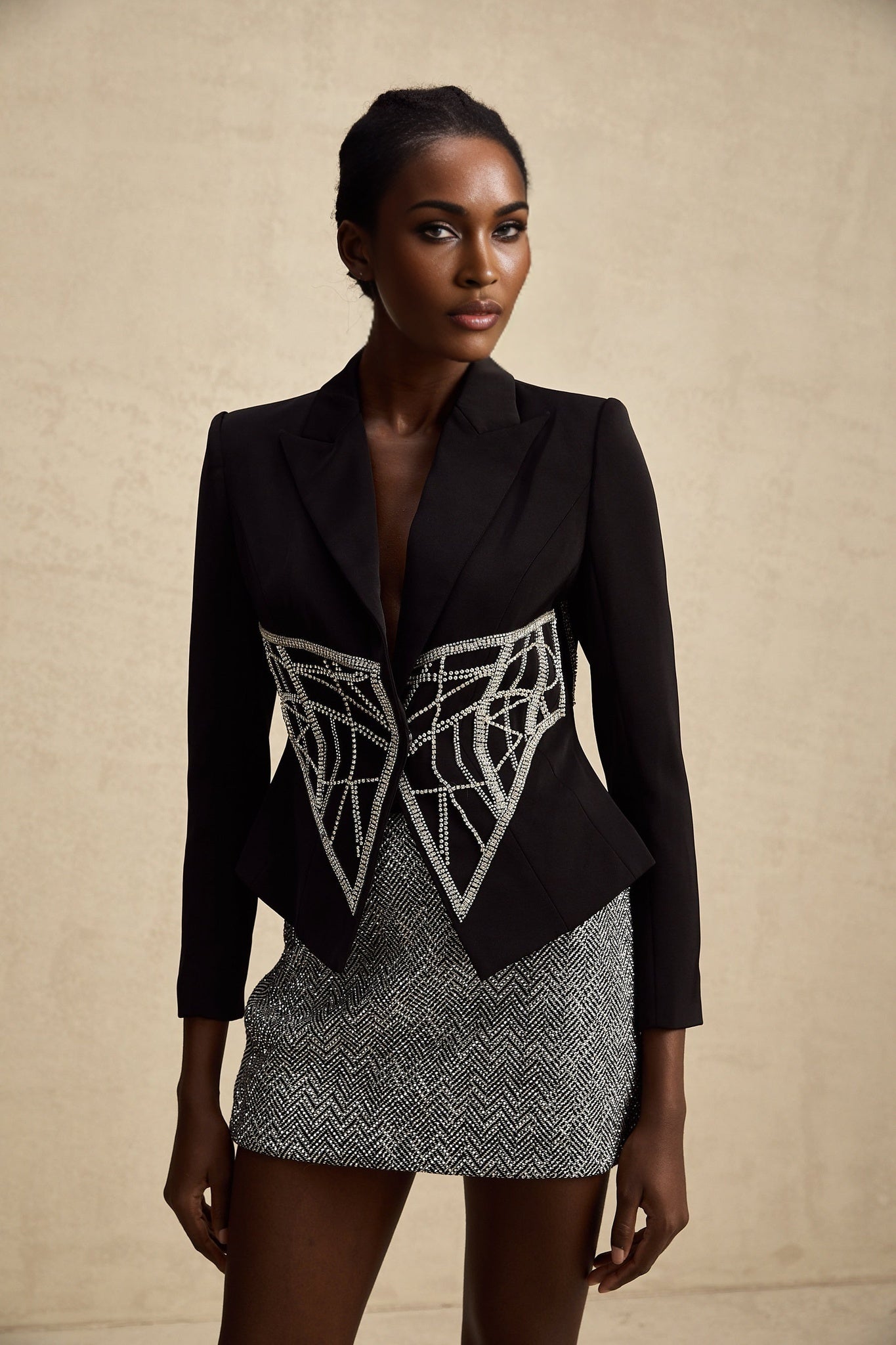 Woman wearing black fitted jacket with embellished details and cinched waist