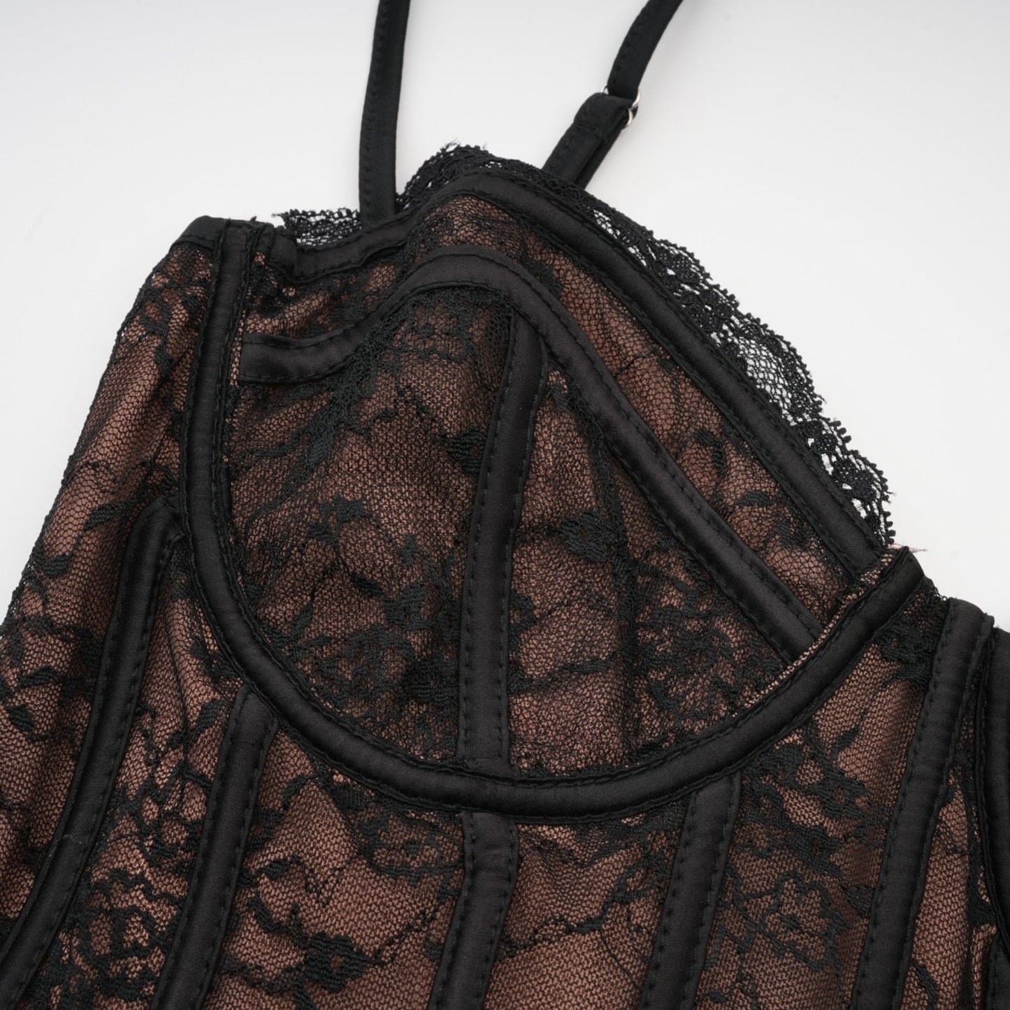 Woman wearing black floral lace sleeveless vest over matching dress with floral lace pattern