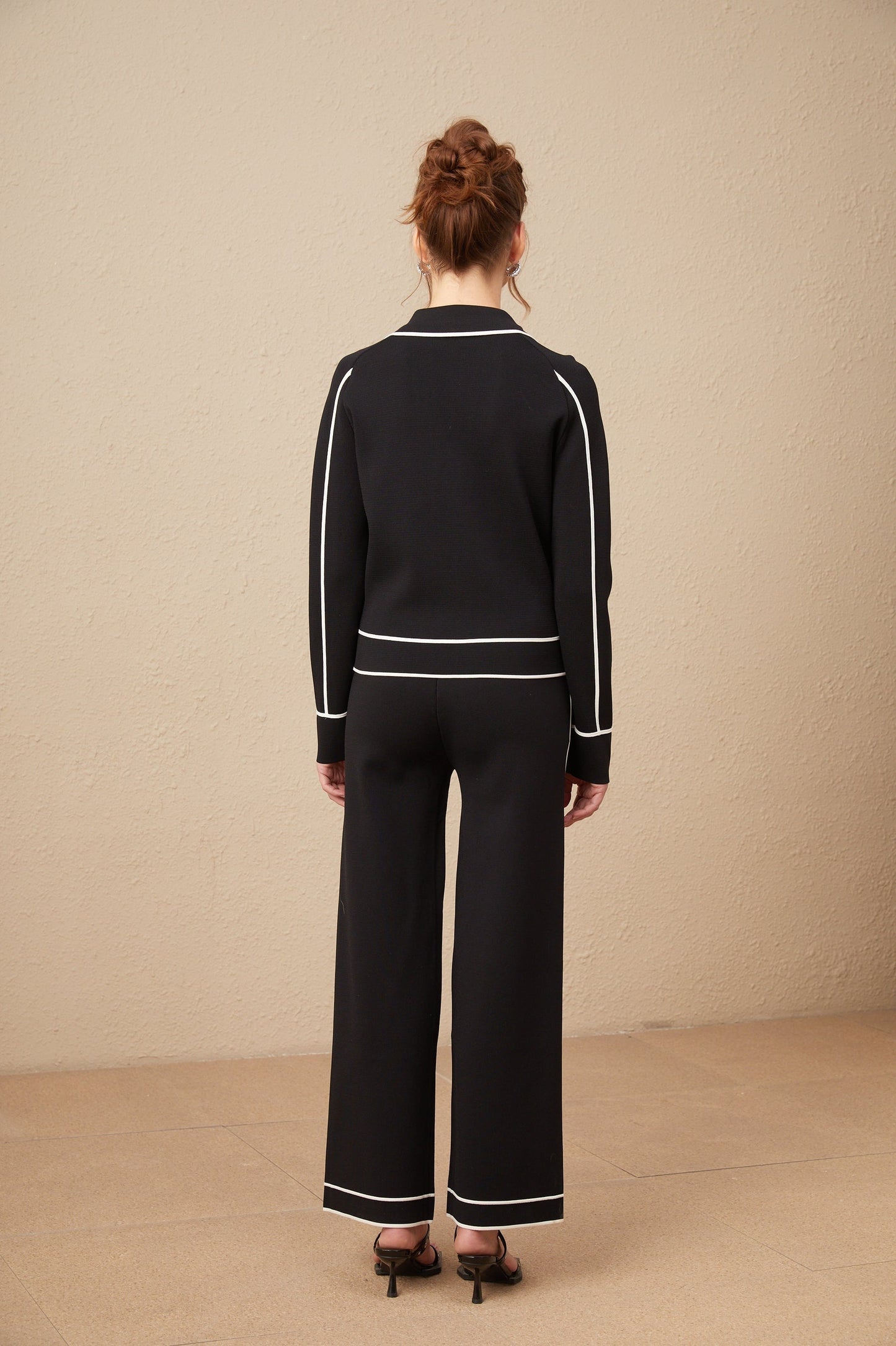 Woman wearing black jacket and trousers set with white piping trim stylish matching outfit