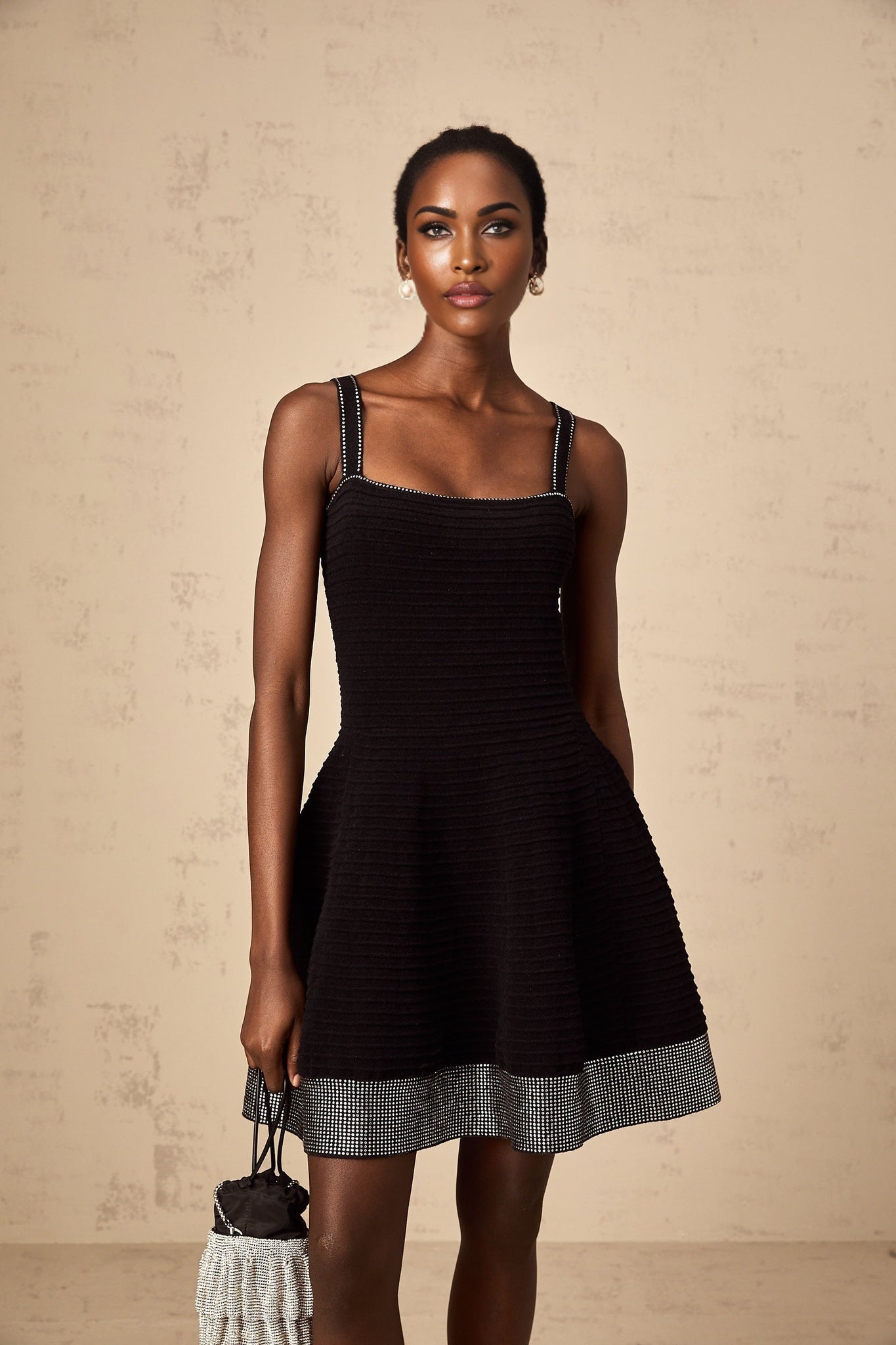 Woman wearing black knit mini dress with flared skirt and studded details