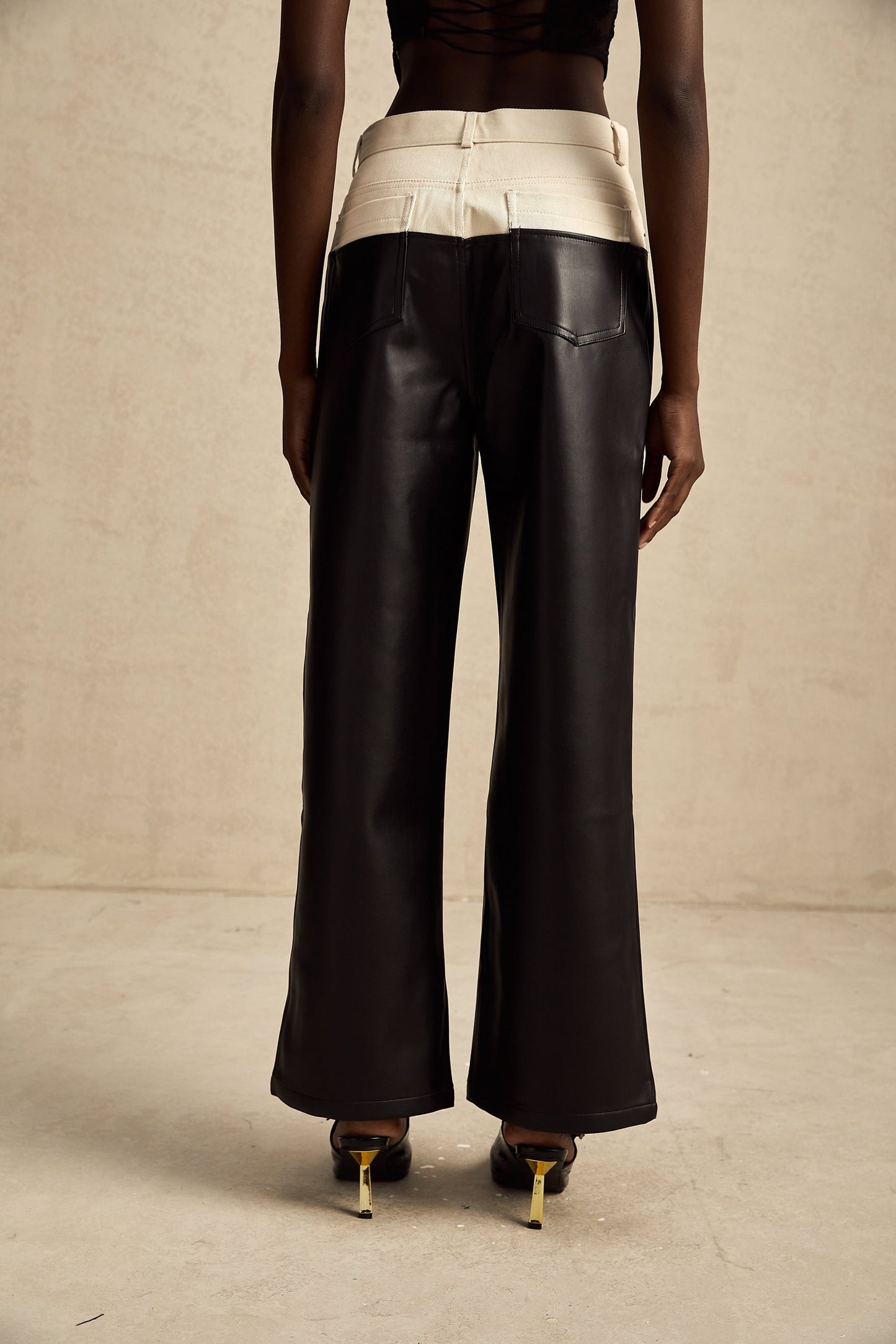 Woman wearing black leather trousers with contrasting white side panels standing in a neutral pose