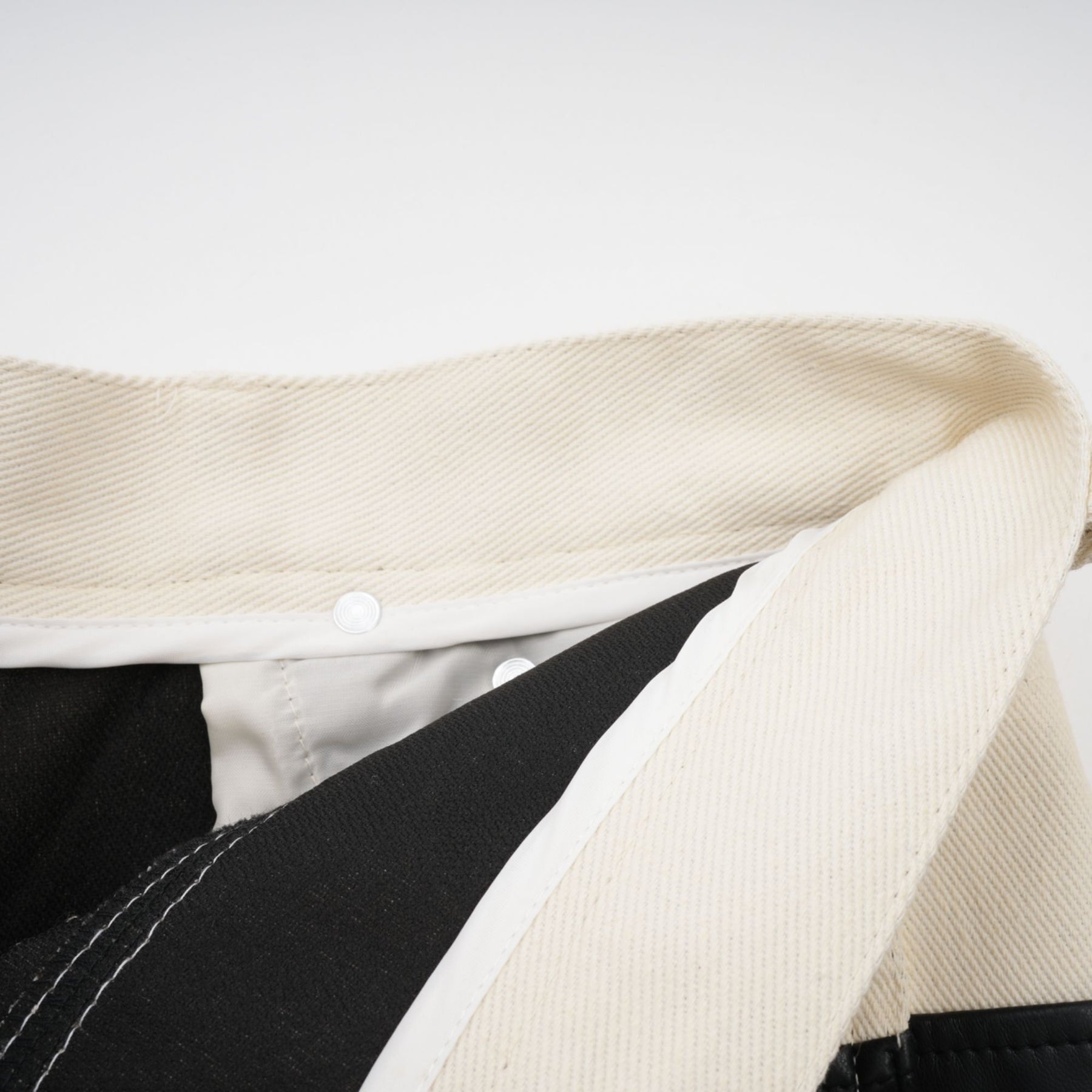 Woman wearing black leather trousers with white contrast panels on the sides standing in a casual pose