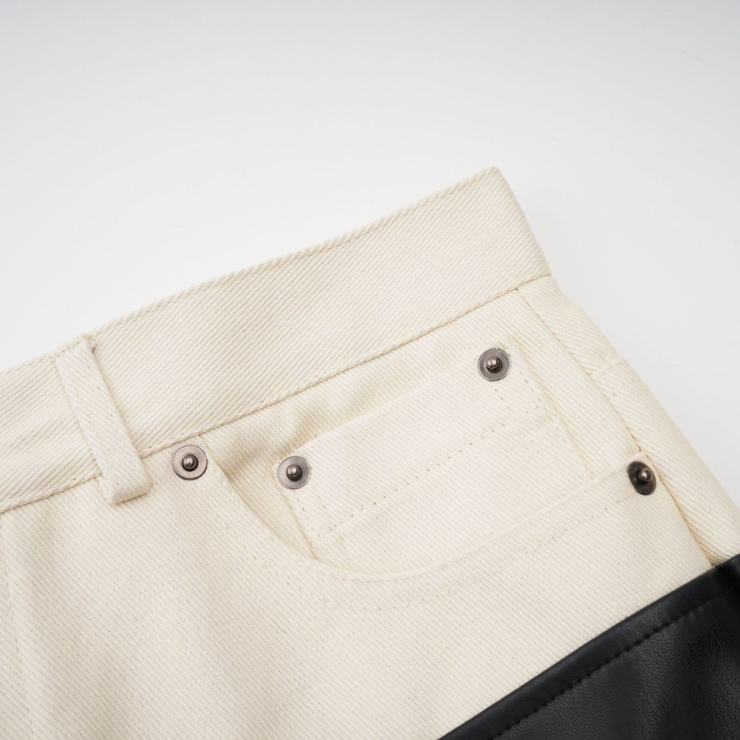 Woman wearing black leather trousers with white contrast panels on the sides standing in a casual pose