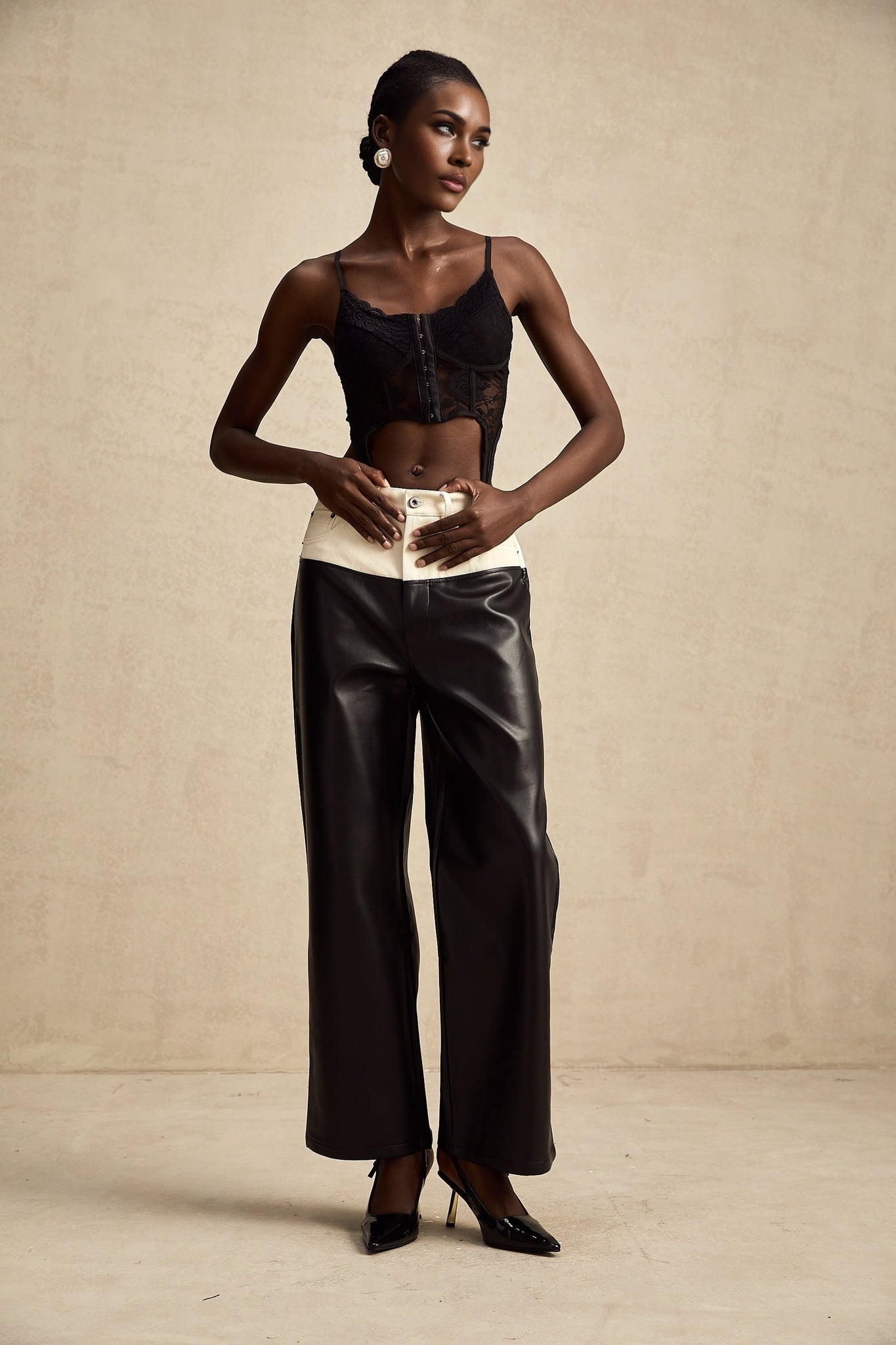 Woman wearing black leather trousers with white side stripes standing in casual pose