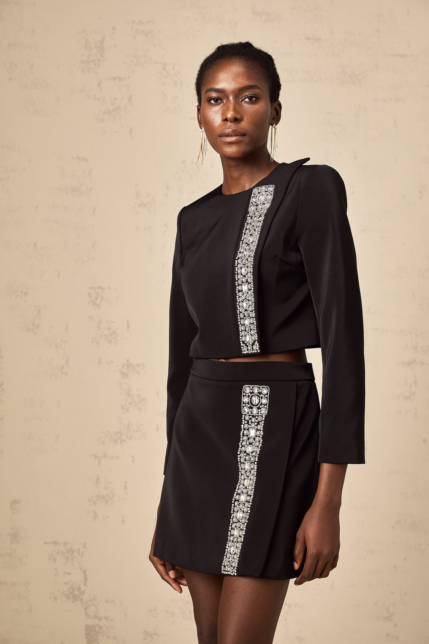 Woman wearing black matching set consisting of crystalembellished top and skirt named Nadia