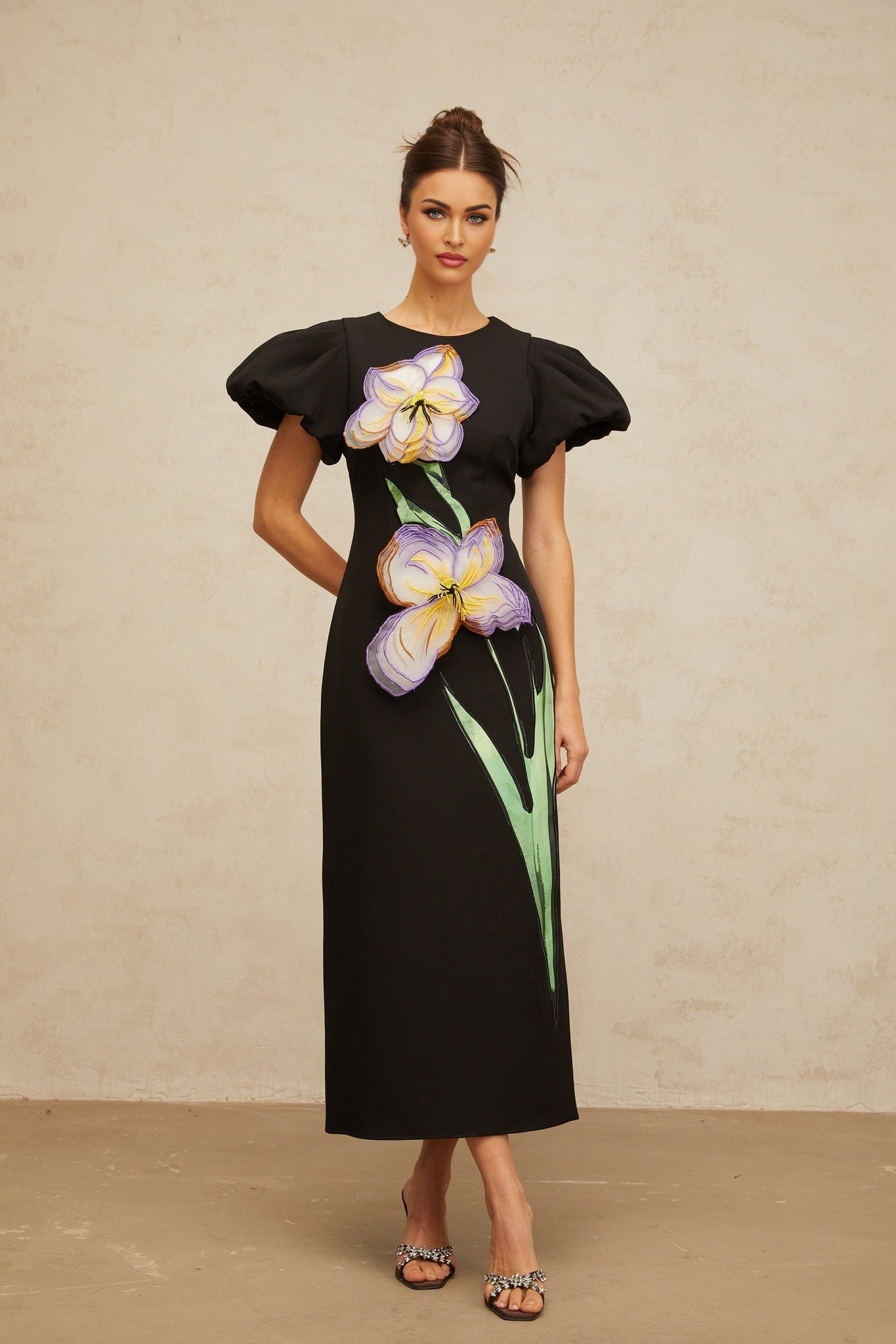 Woman wearing black midi dress with sequined floral embroidery standing in elegant pose