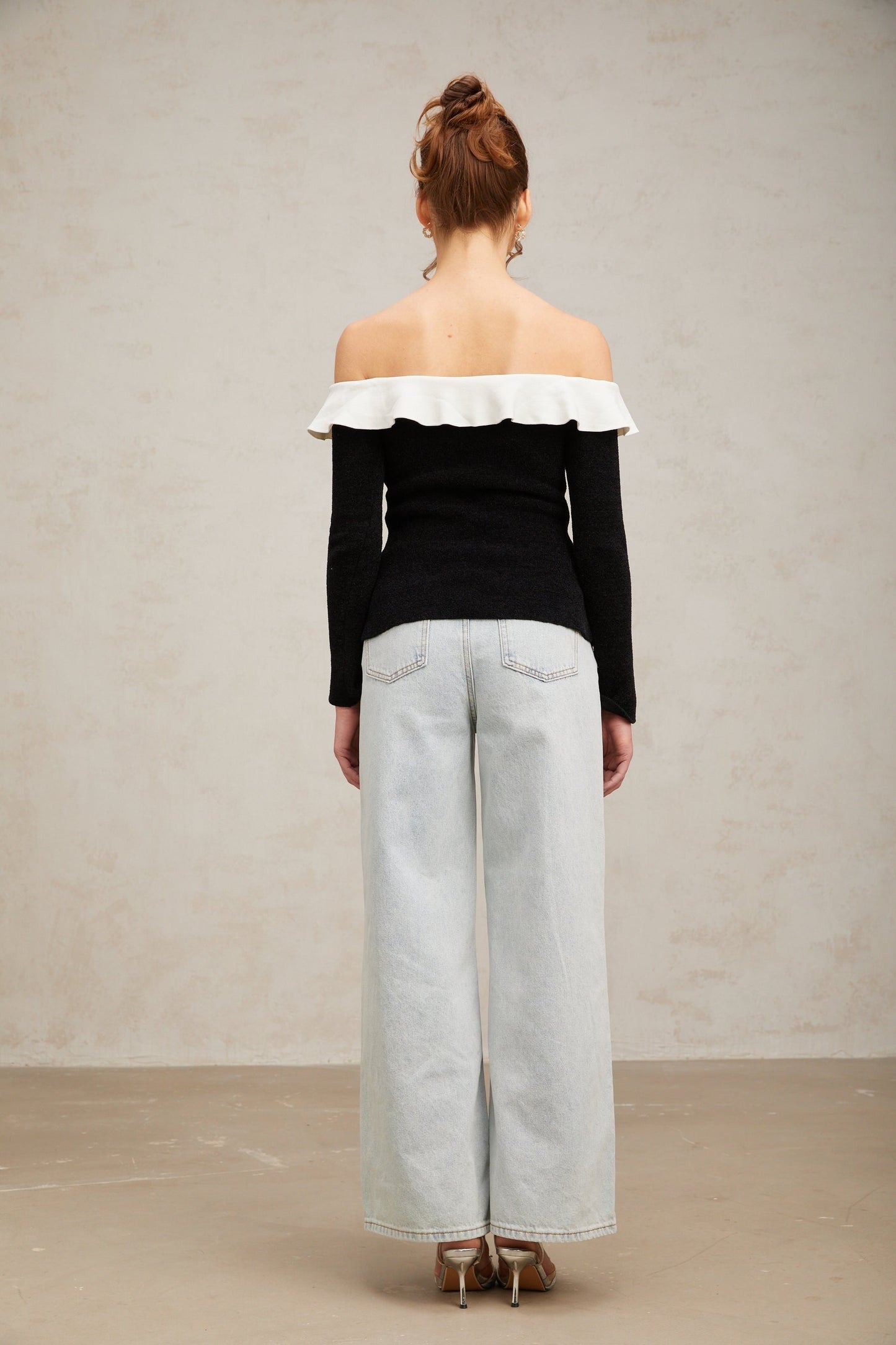 Woman wearing black offshoulder top with ruffle detail