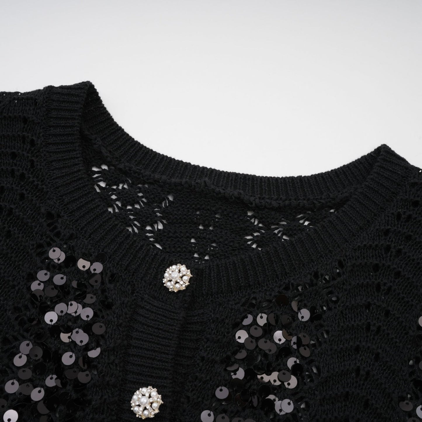 Woman wearing black sequined cardigan and matching skirt set with crochet knit pattern
