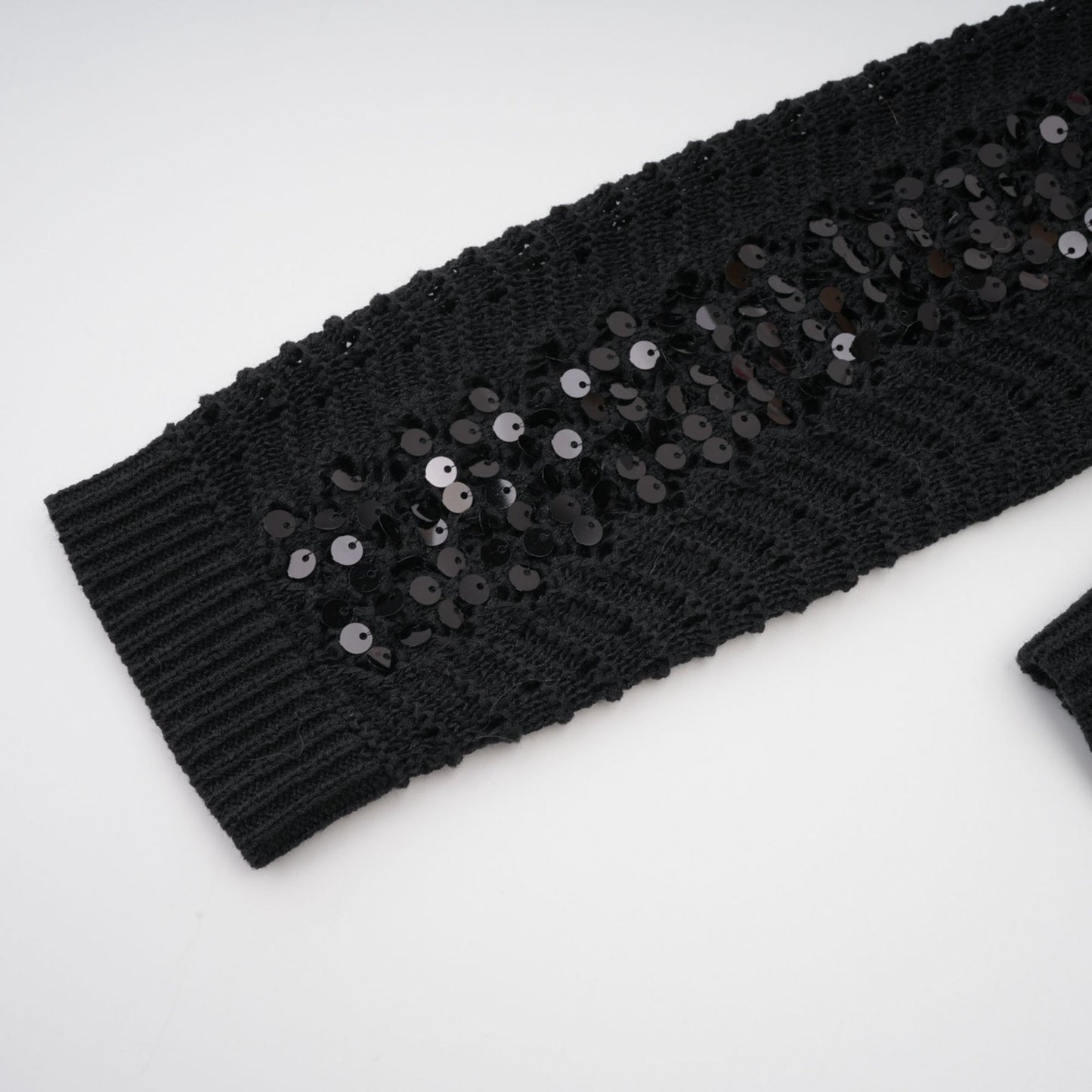 Woman wearing black sequined crochet cardigan and matching skirt set with sparkly texture