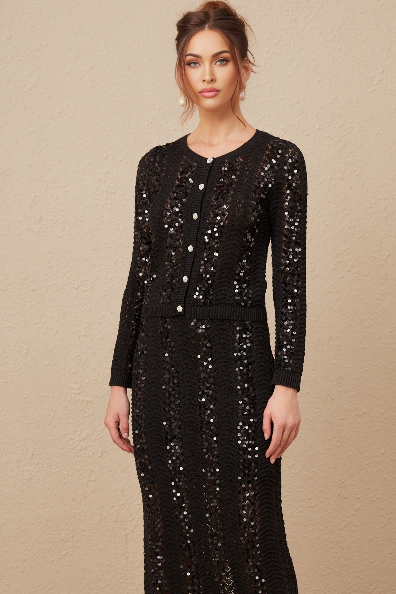 Woman wearing black sequined crochet knit cardigan and matching skirt set