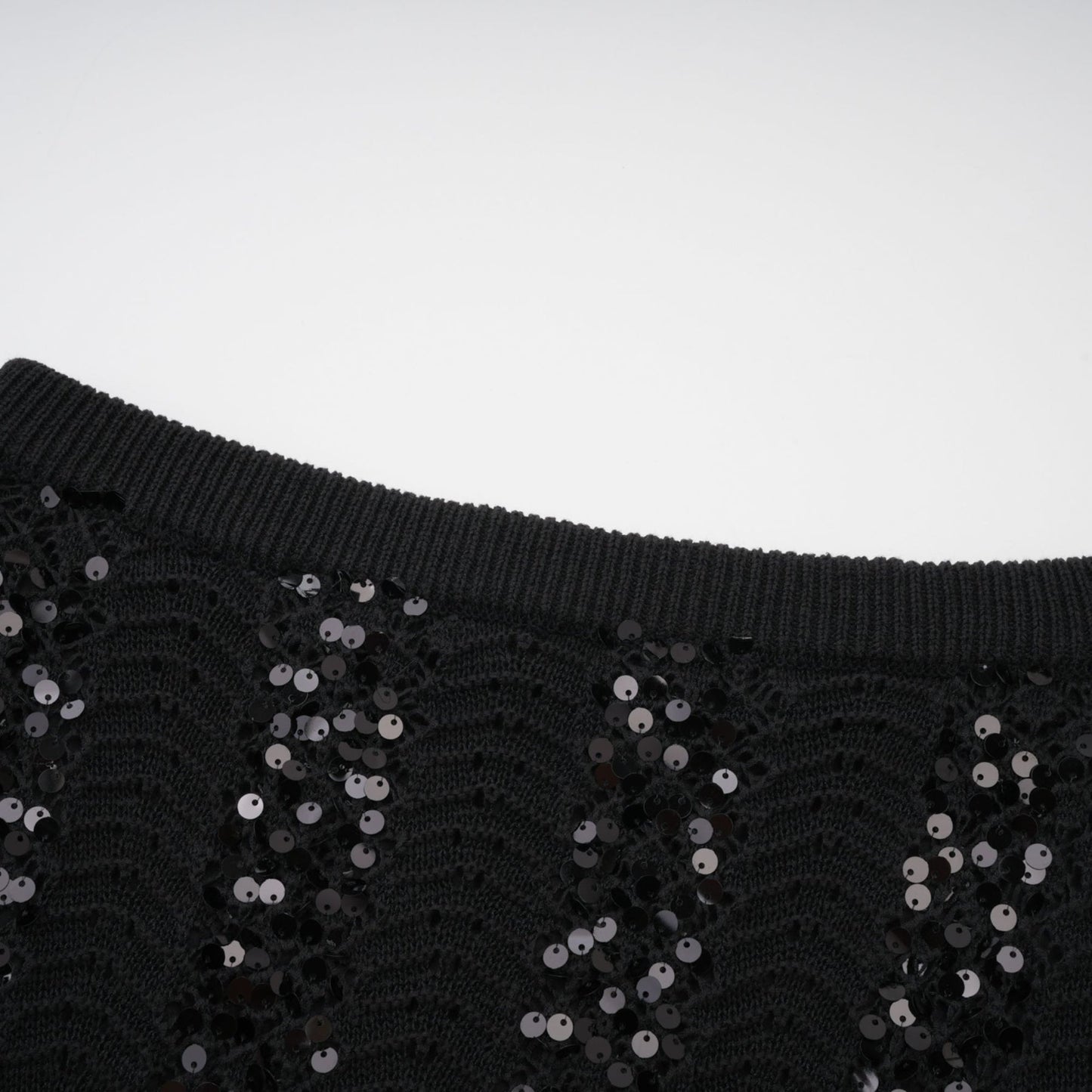 Woman wearing black sequined crochet knit cardigan and matching skirt set