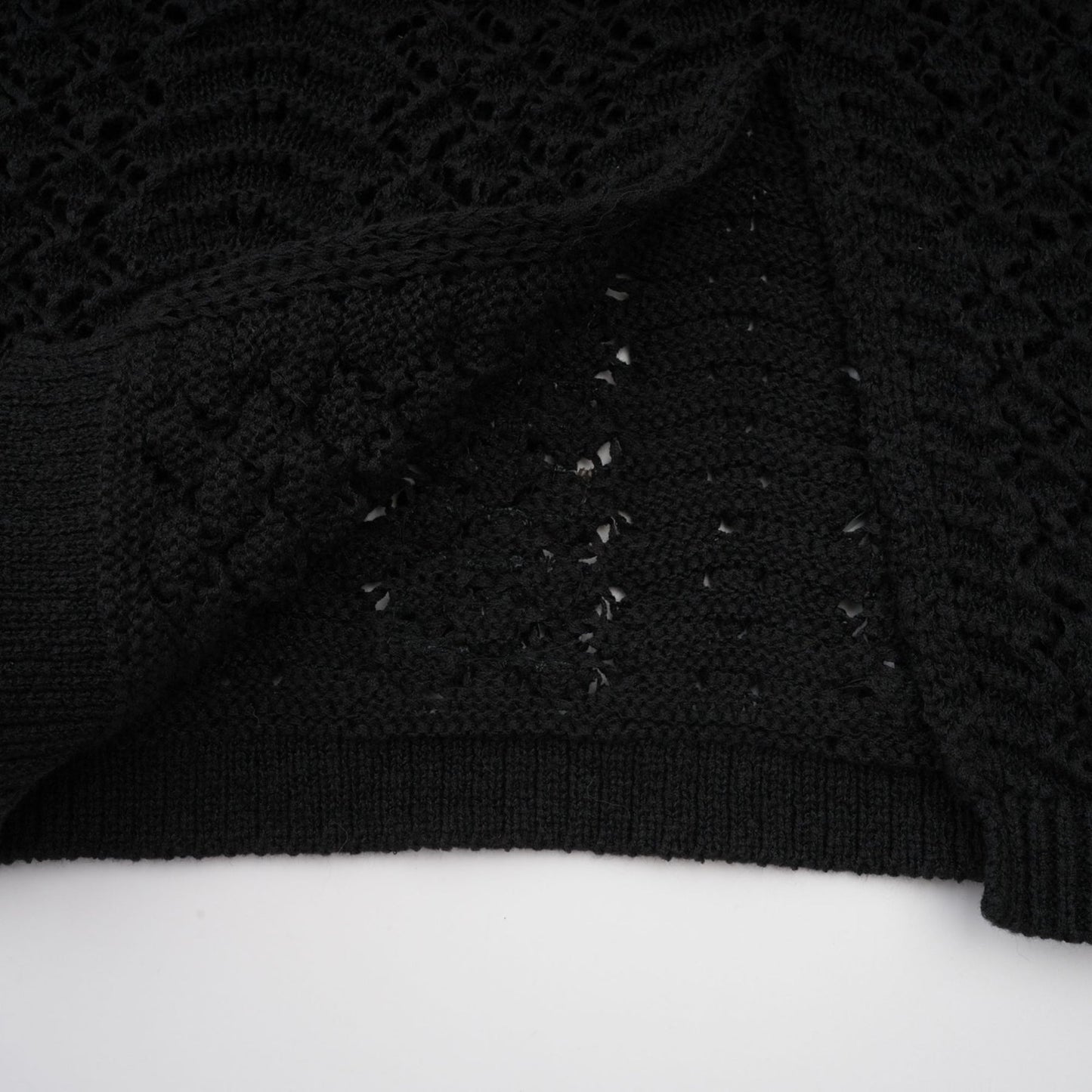 Woman wearing black sequined crochet knit cardigan and matching skirt set