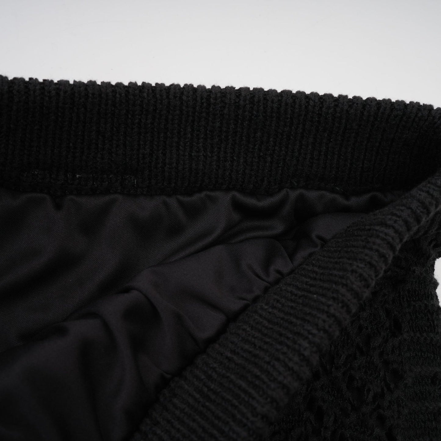 Woman wearing black sequined crochet knit cardigan and matching skirt set