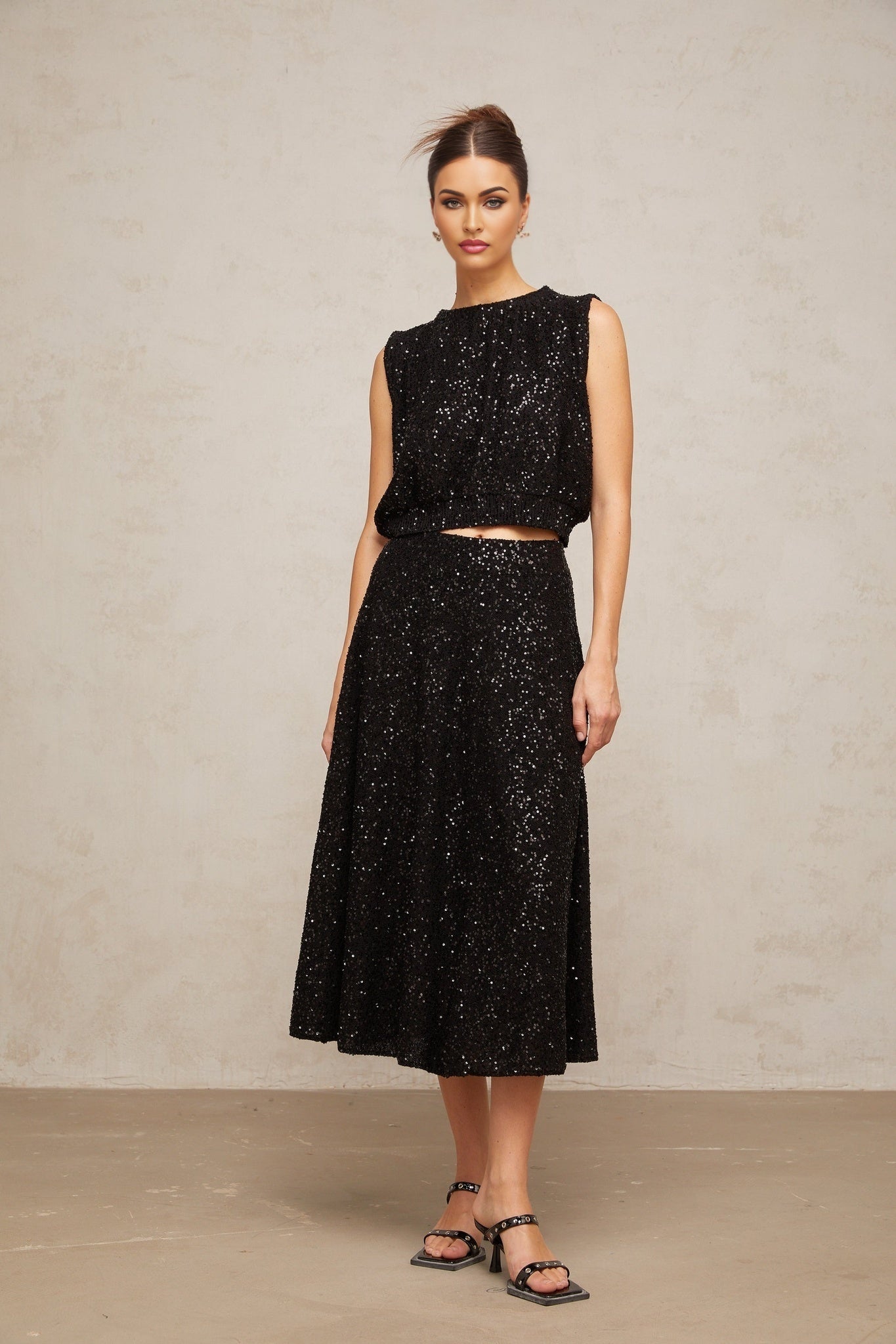 Woman wearing black sequined knit vest and matching skirt set Ulrique brand outfit shimmering formal attire