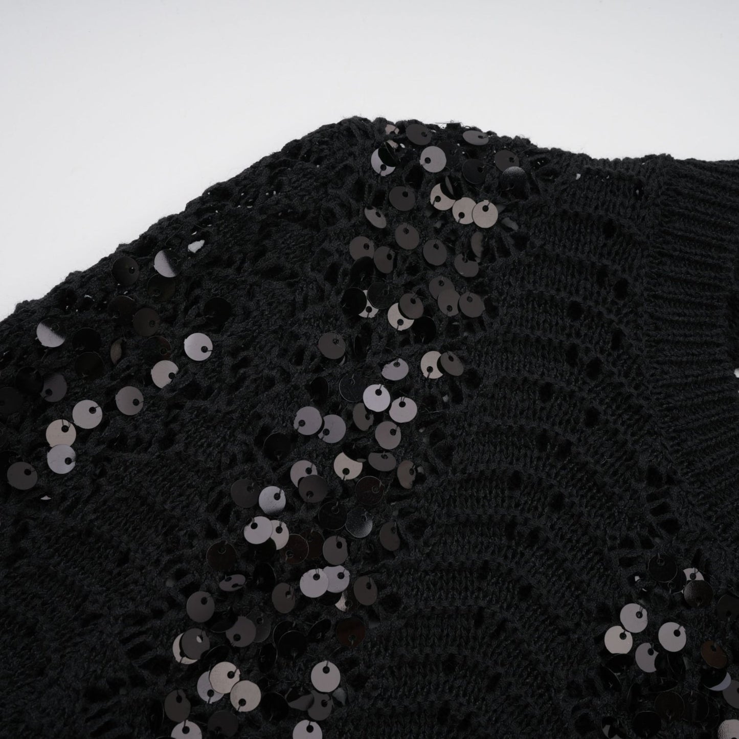 Woman wearing black sequined matching set with crochet knit cardigan and skirt