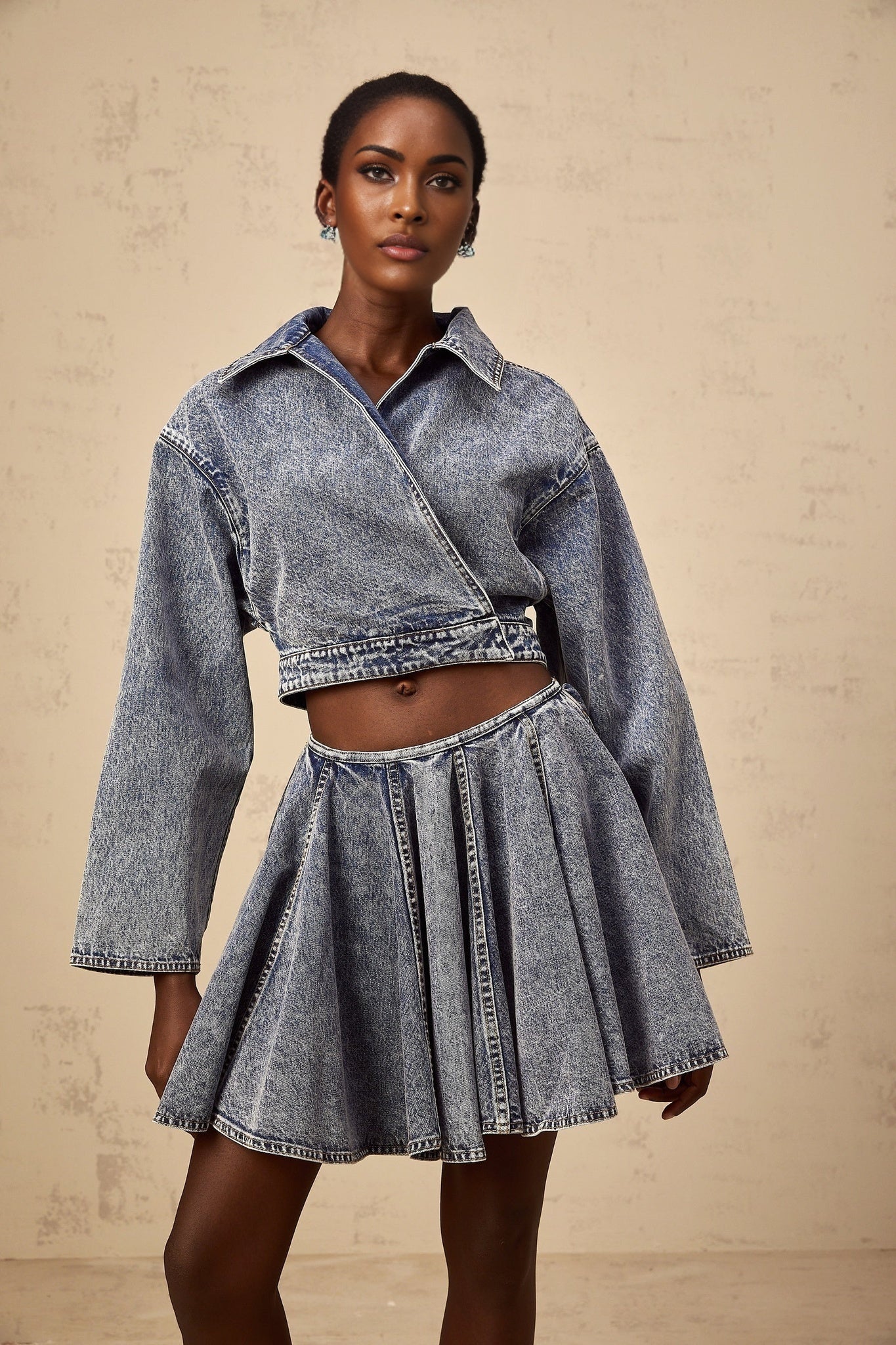 Woman wearing blue cropped denim jacket with asymmetrical design and frayed edges