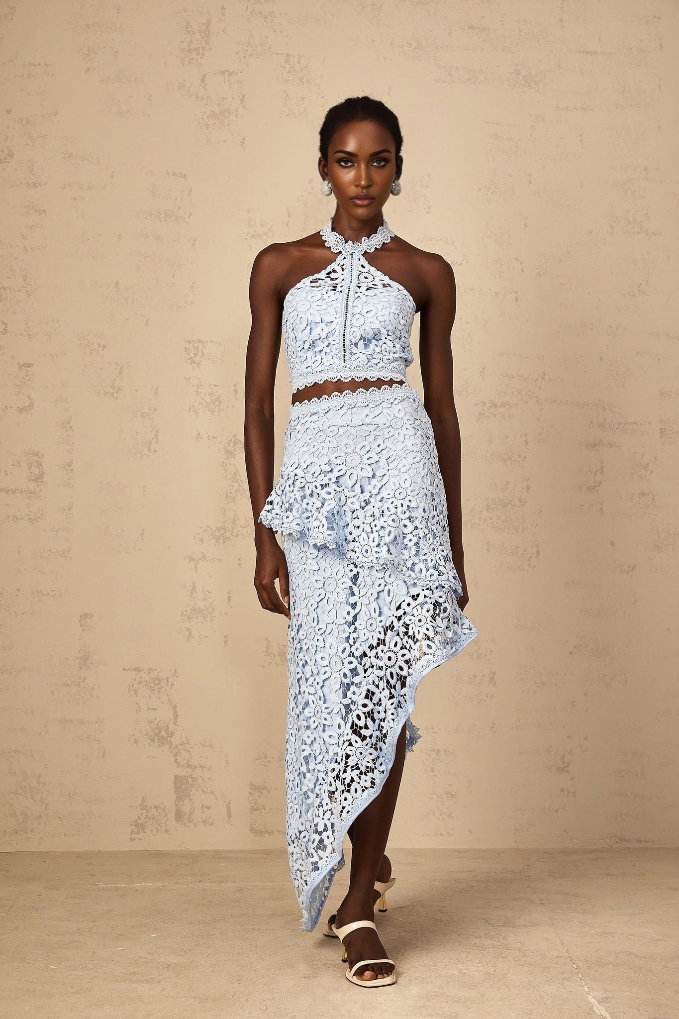 Woman wearing blue lace matching set with corded details top and bottom pieces visible against plain background