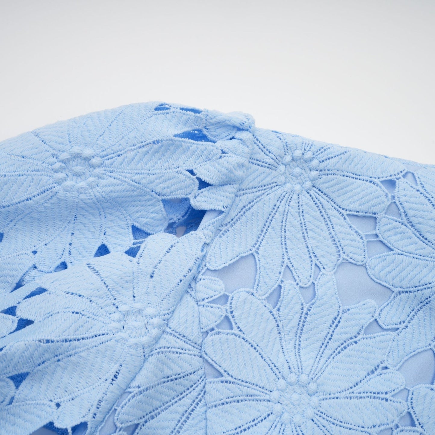 Woman wearing blue lace matching top and skirt set with floral pattern and scalloped edges