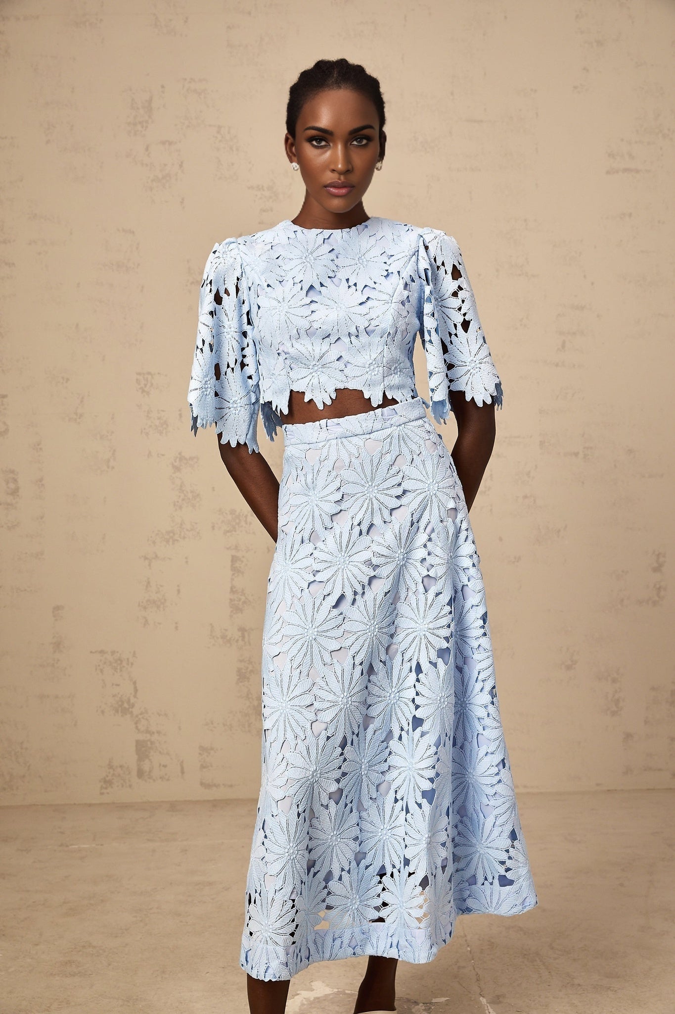 Woman wearing blue lace matching top and skirt set with floral pattern and scalloped edges
