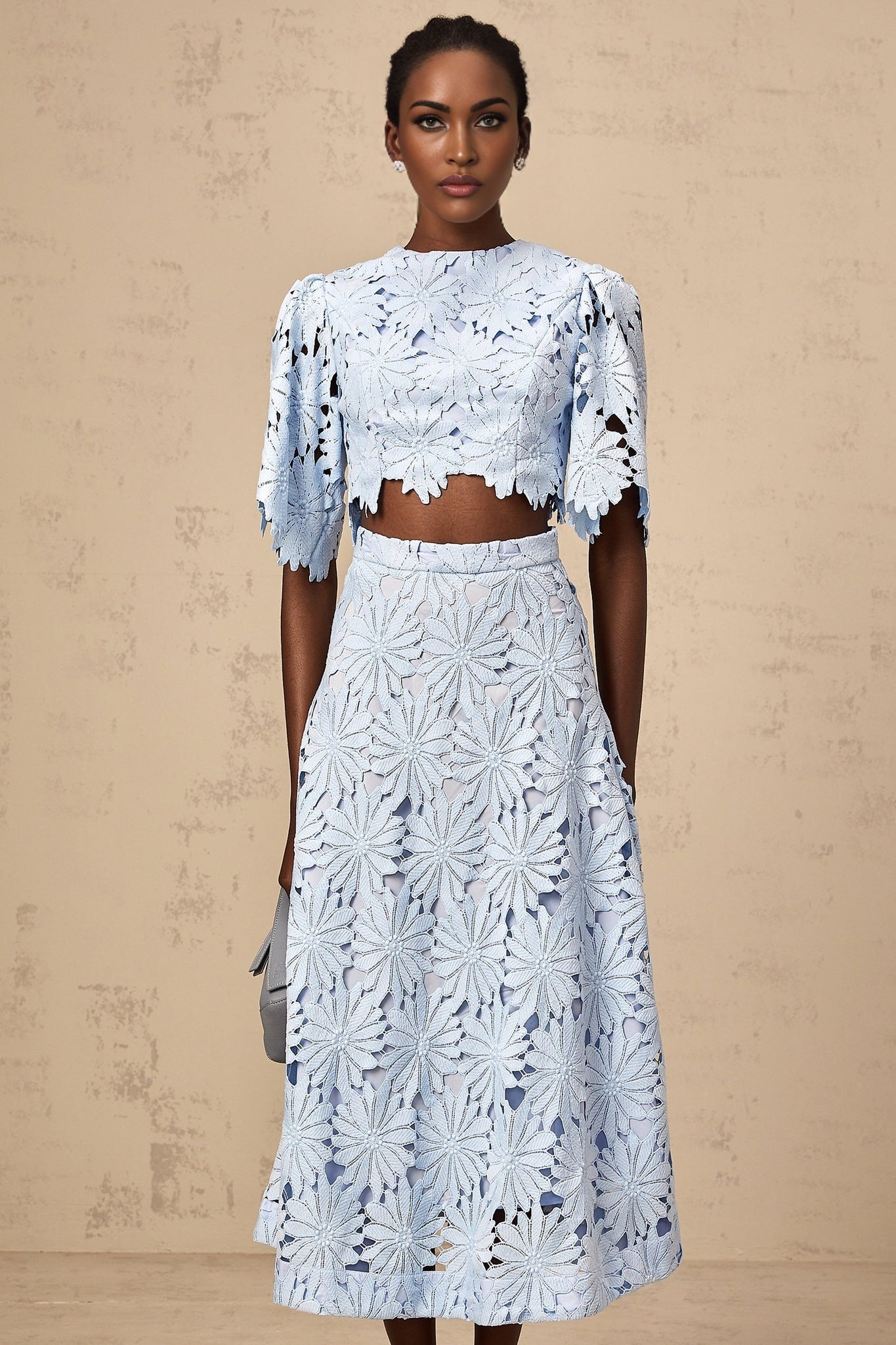 Woman wearing blue lace top and matching skirt set named Audrey with intricate guipure lace pattern