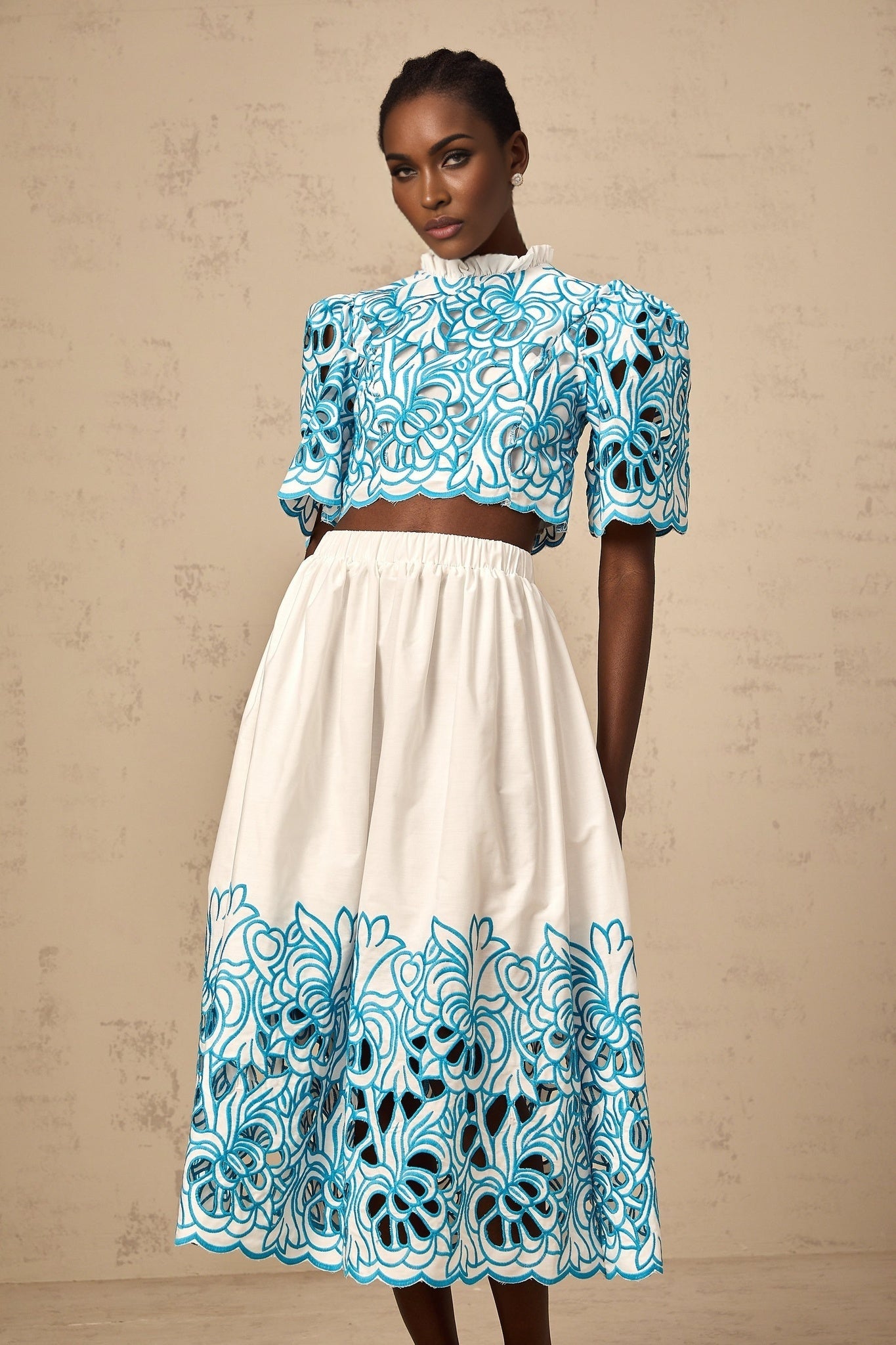 Woman wearing blue matching set with embroidered top and skirt featuring cutout details