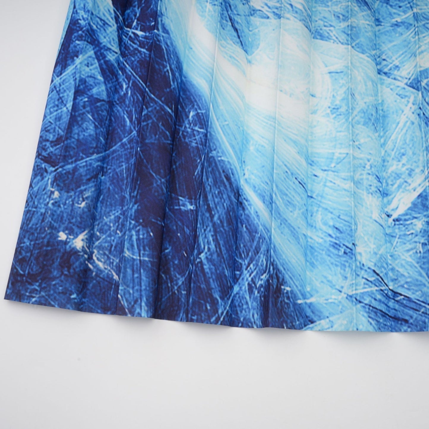 Woman wearing blue patterned cape and matching skirt set with crease details and allover print design