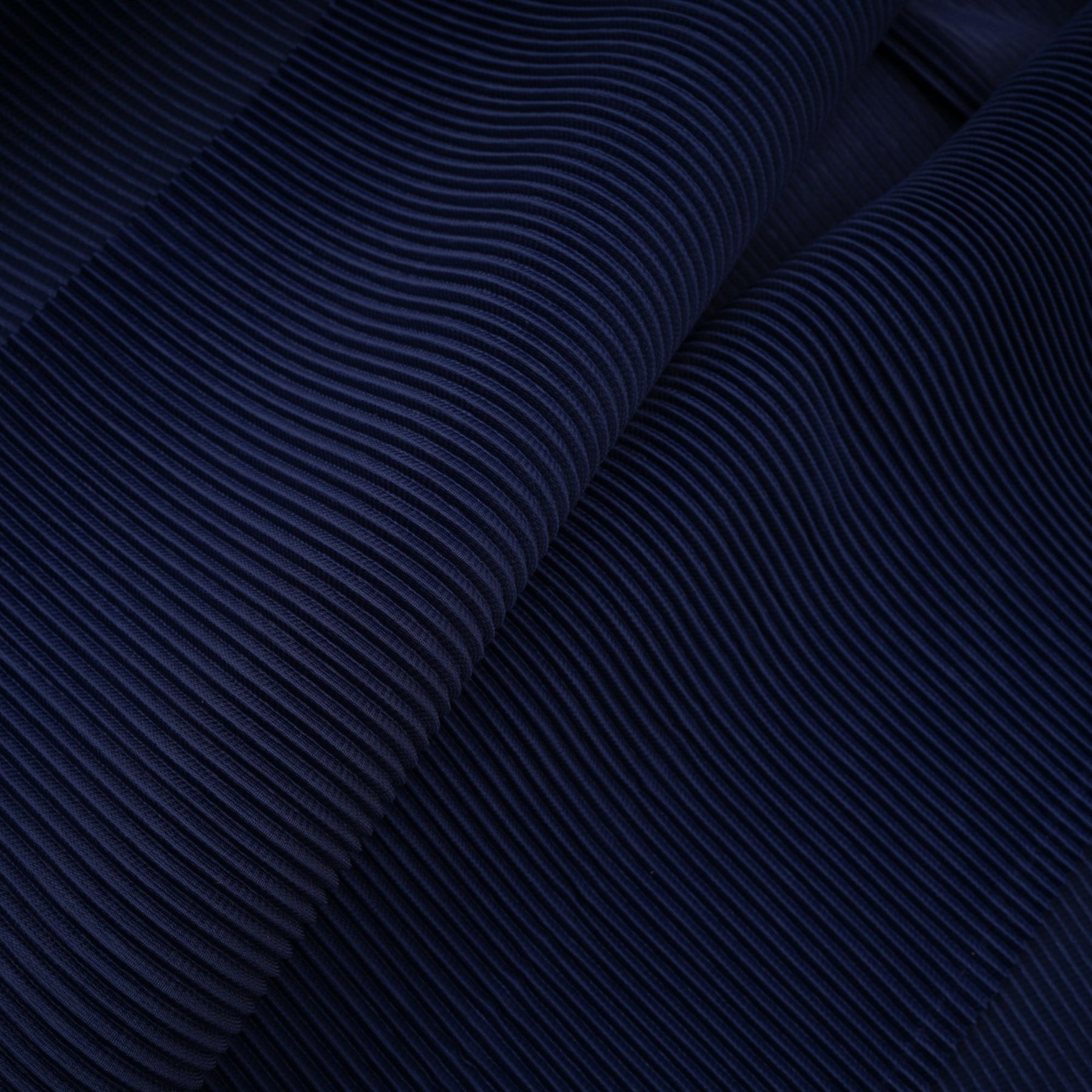 Woman wearing blue patterned cape and matching skirt set with creased fabric design