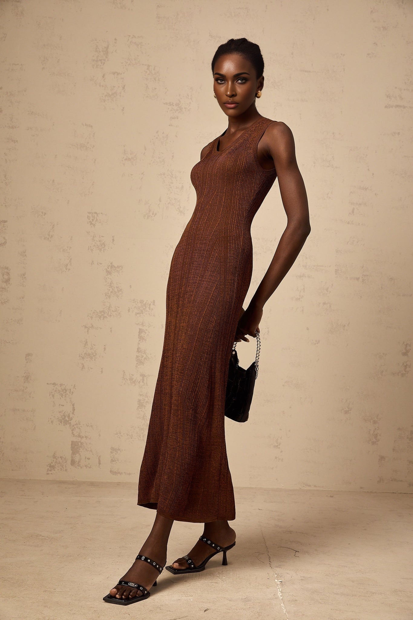 Woman wearing brown knitted midi dress with cut out details sleeveless design and form fitting silhouette