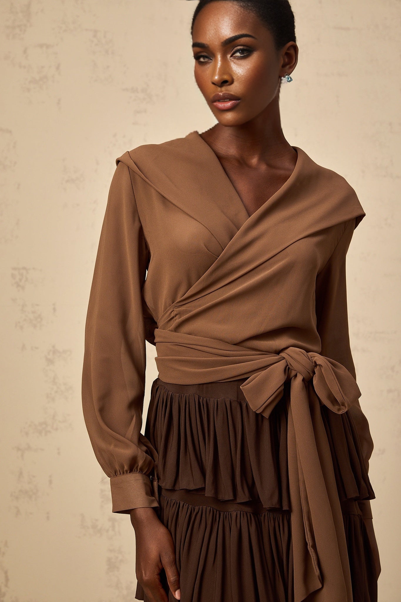 Woman wearing brown semi sheer hooded wrap top with long sleeves and draping front