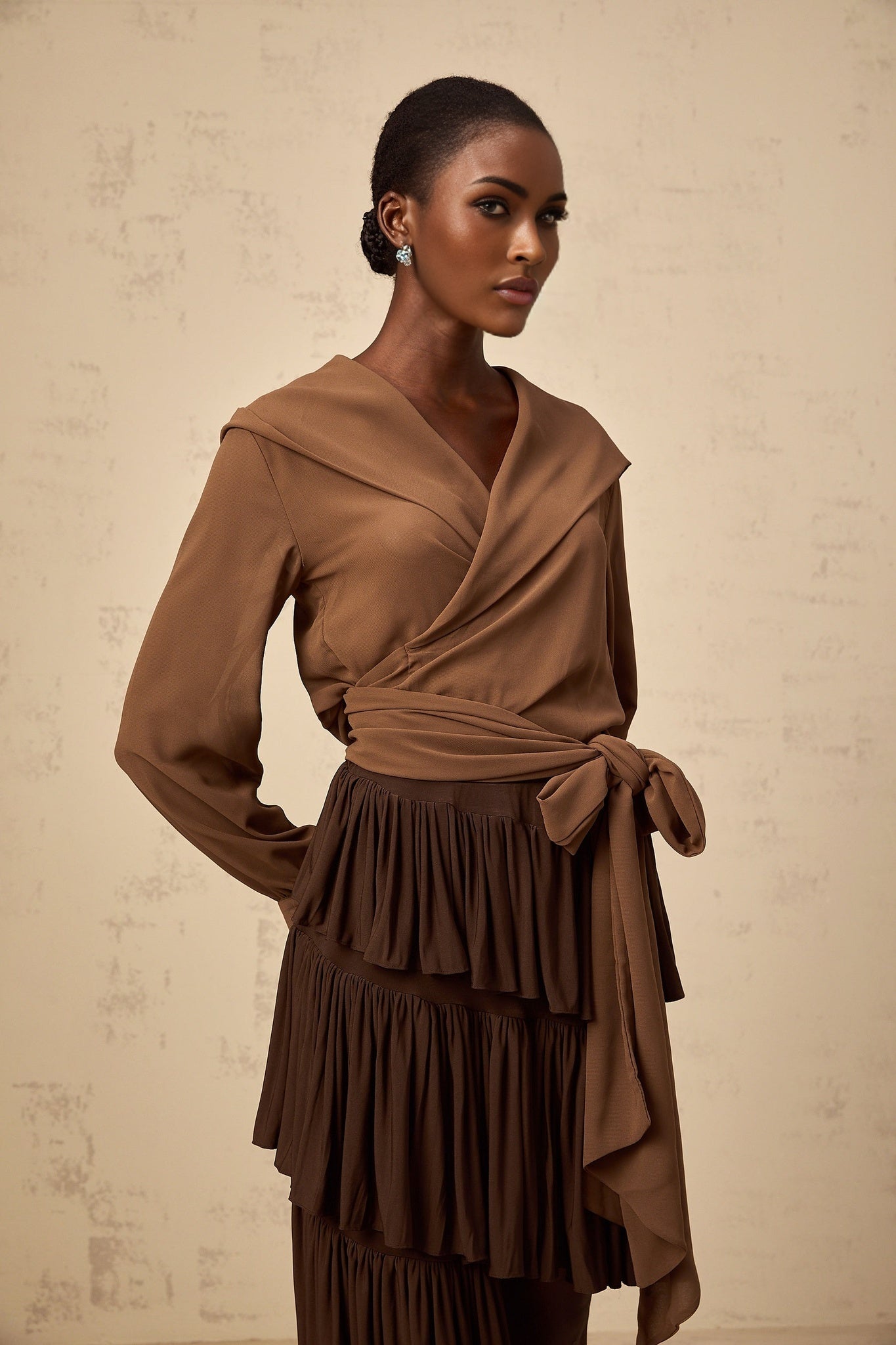Woman wearing brown semi sheer hooded wrap top with long sleeves and tie waist