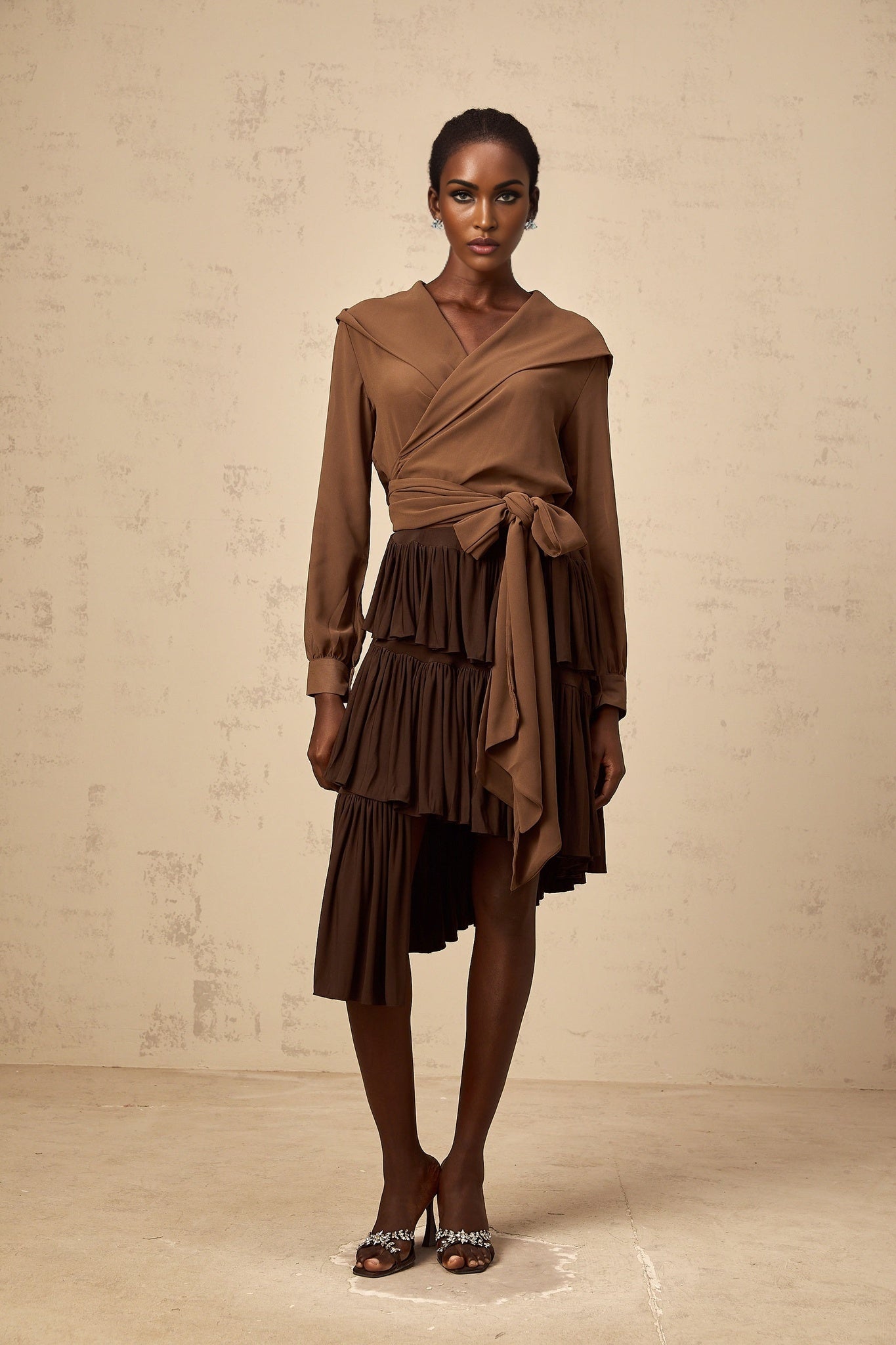 Woman wearing brown semisheer hooded wrap top with long sleeves and cinched waist