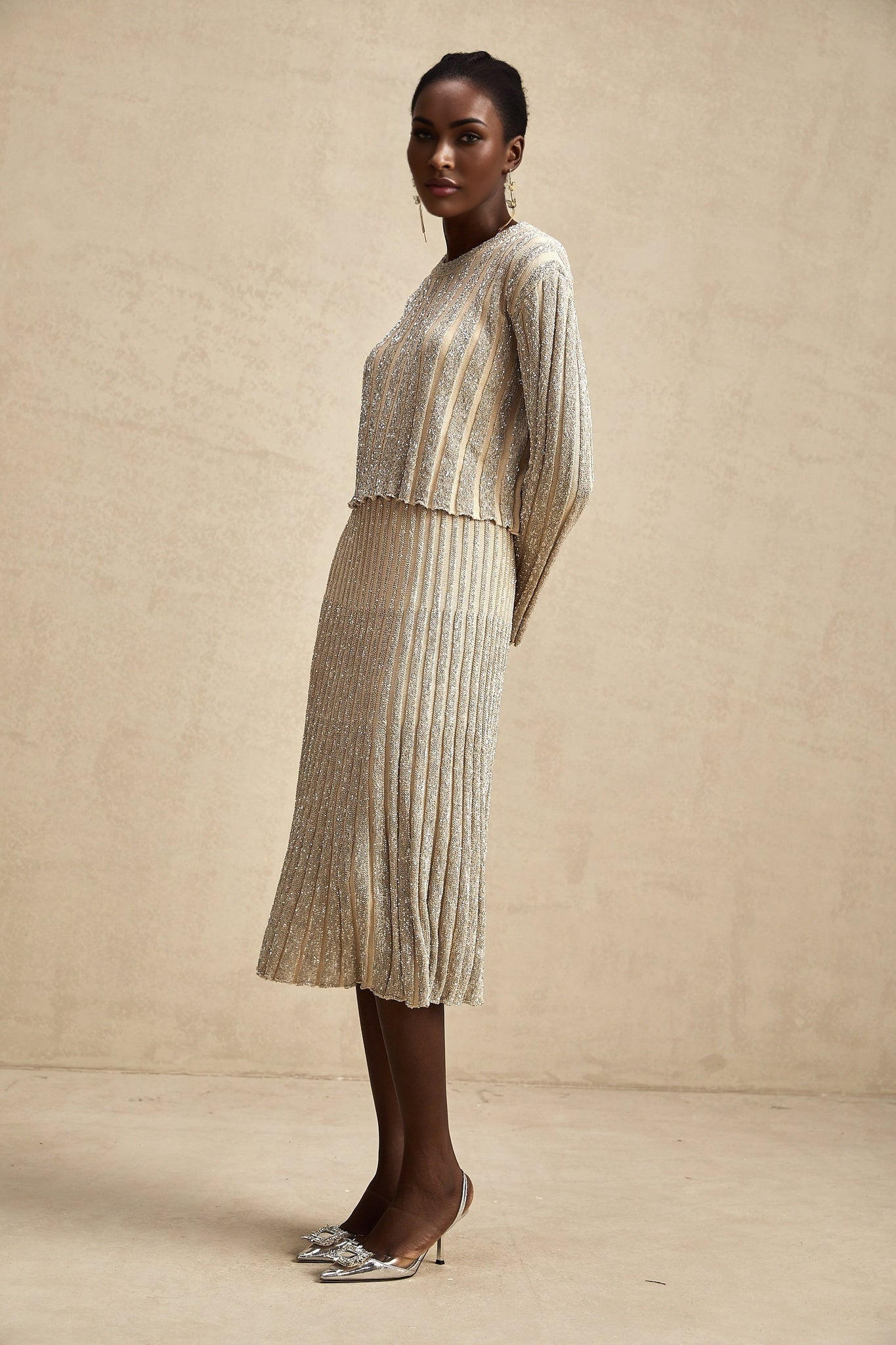 Woman wearing champagne colored knit top and skirt set with vertical stripes in matching pattern